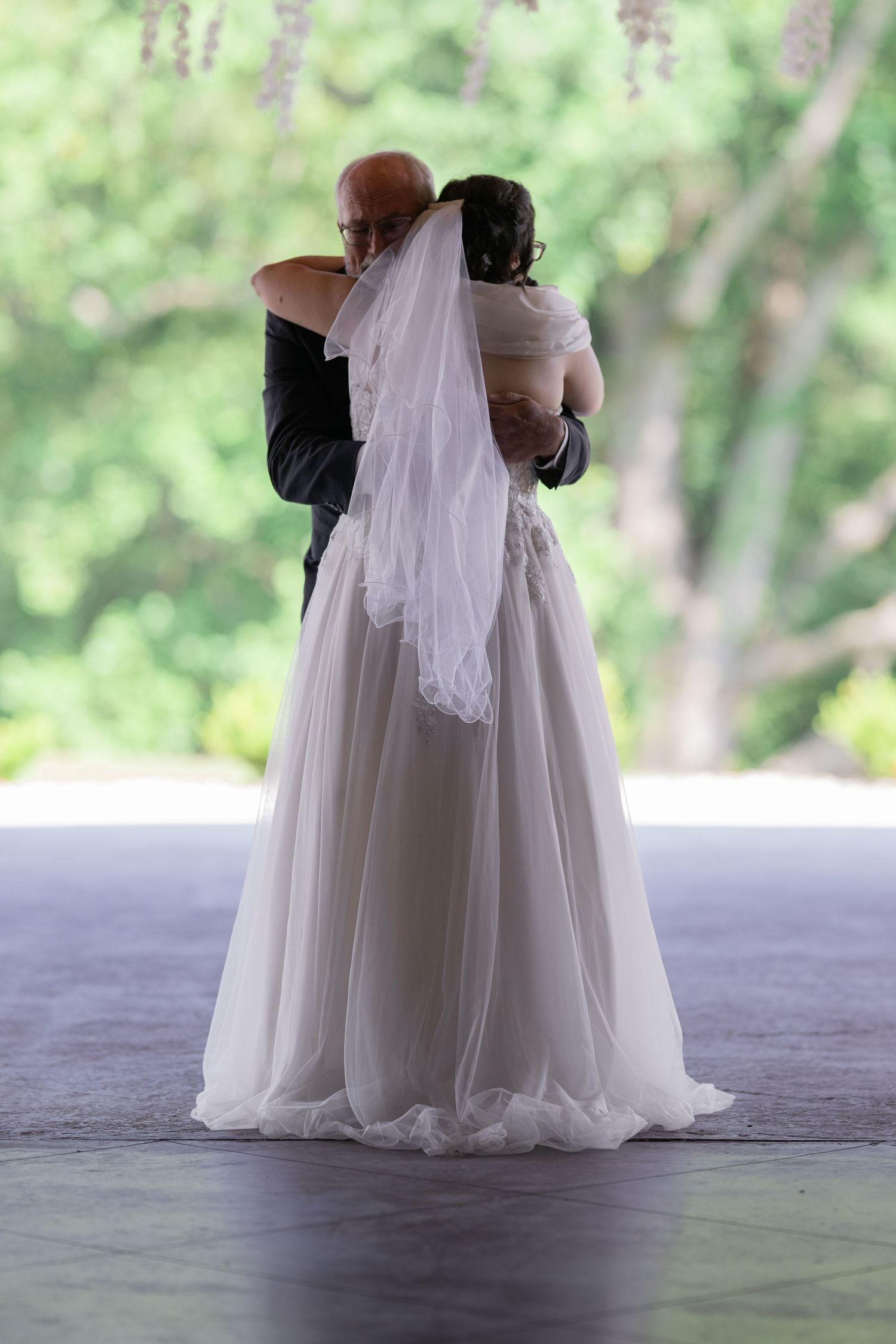 Bride and groom sharing their first dance outdoors, with the bride in a flowing white gown and veil.