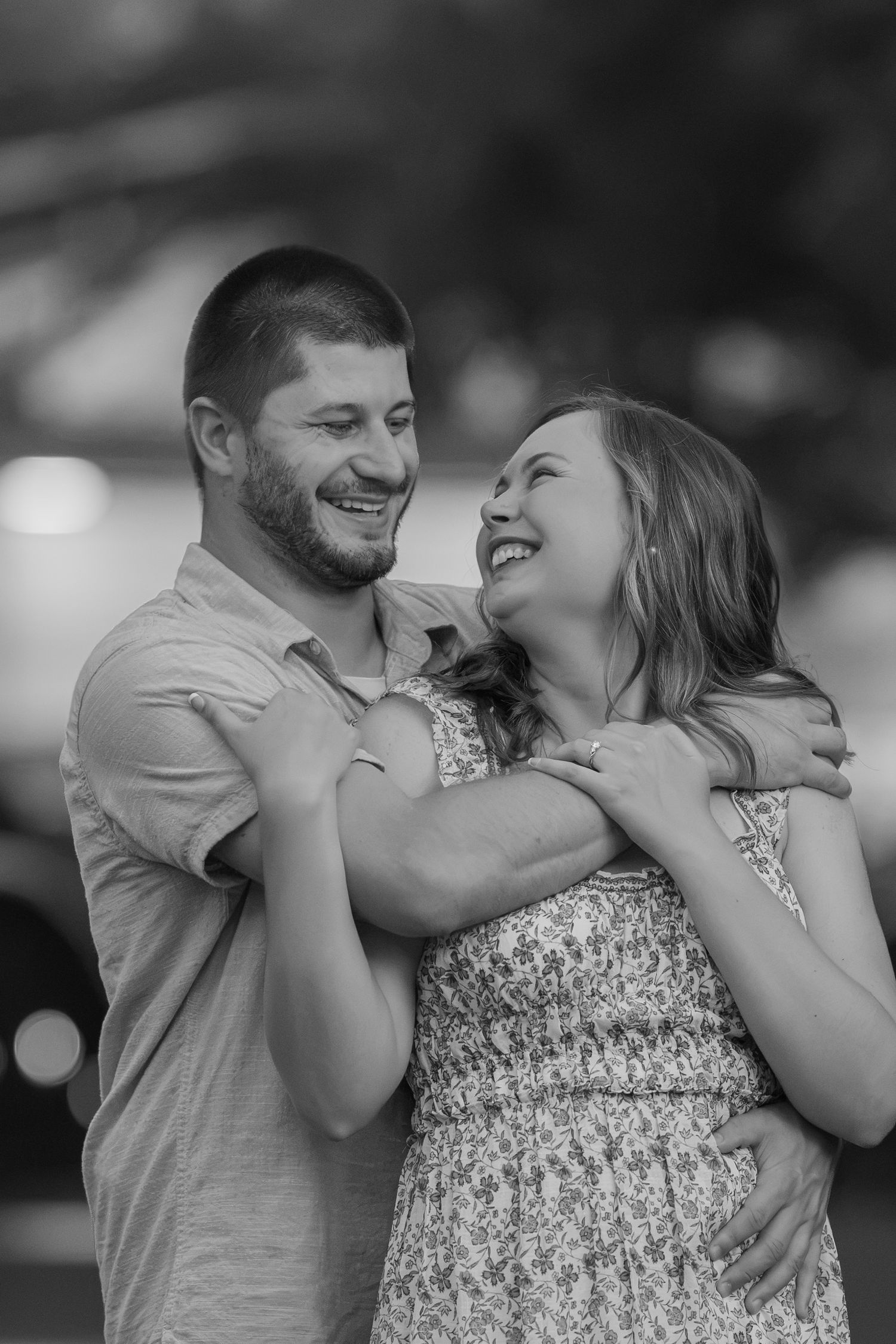 Black and white photo of a happy couple embracing and laughing together outdoors.