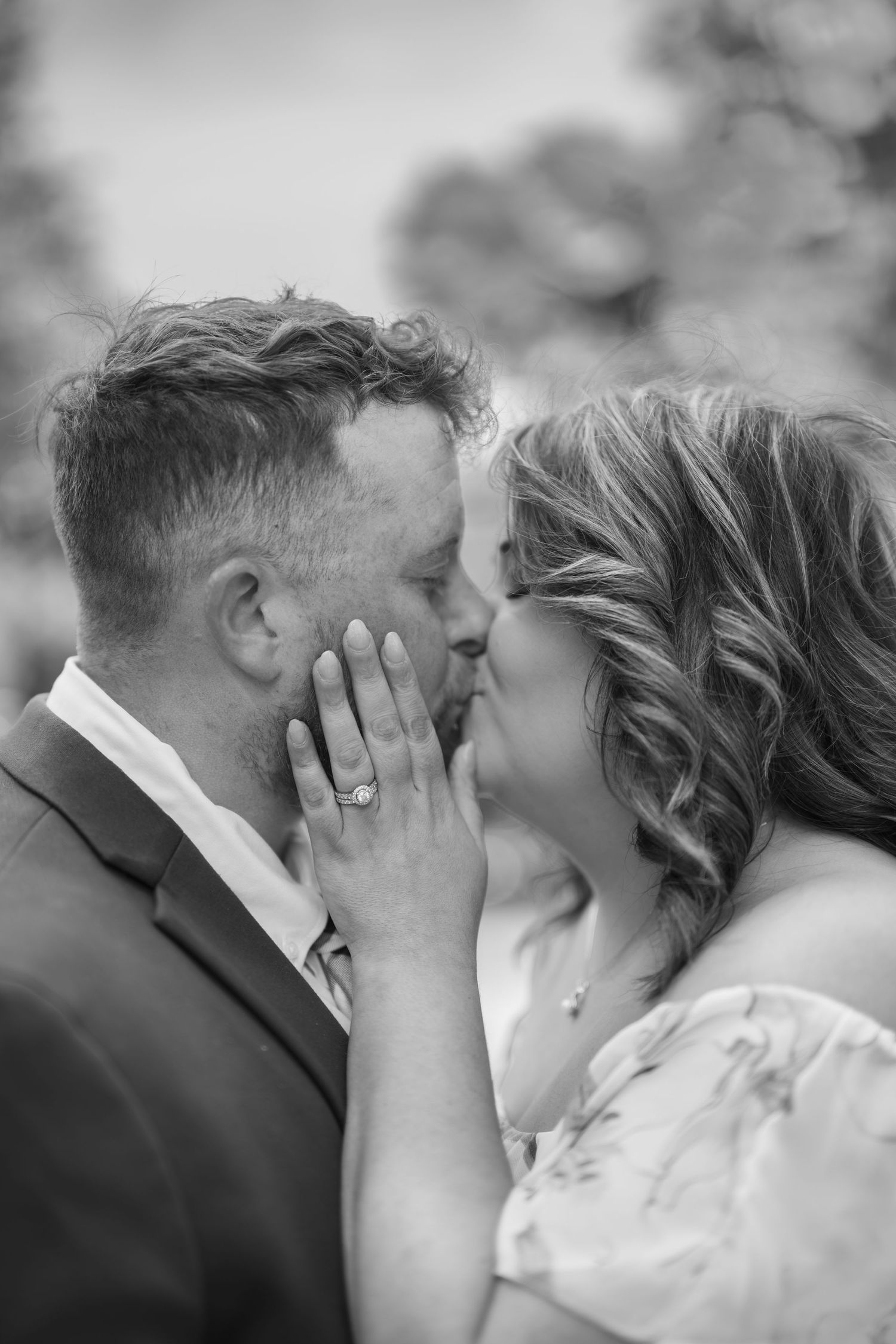 Black and white close-up of a couple sharing a romantic moment, bride's diamond ring visible on groom's face.