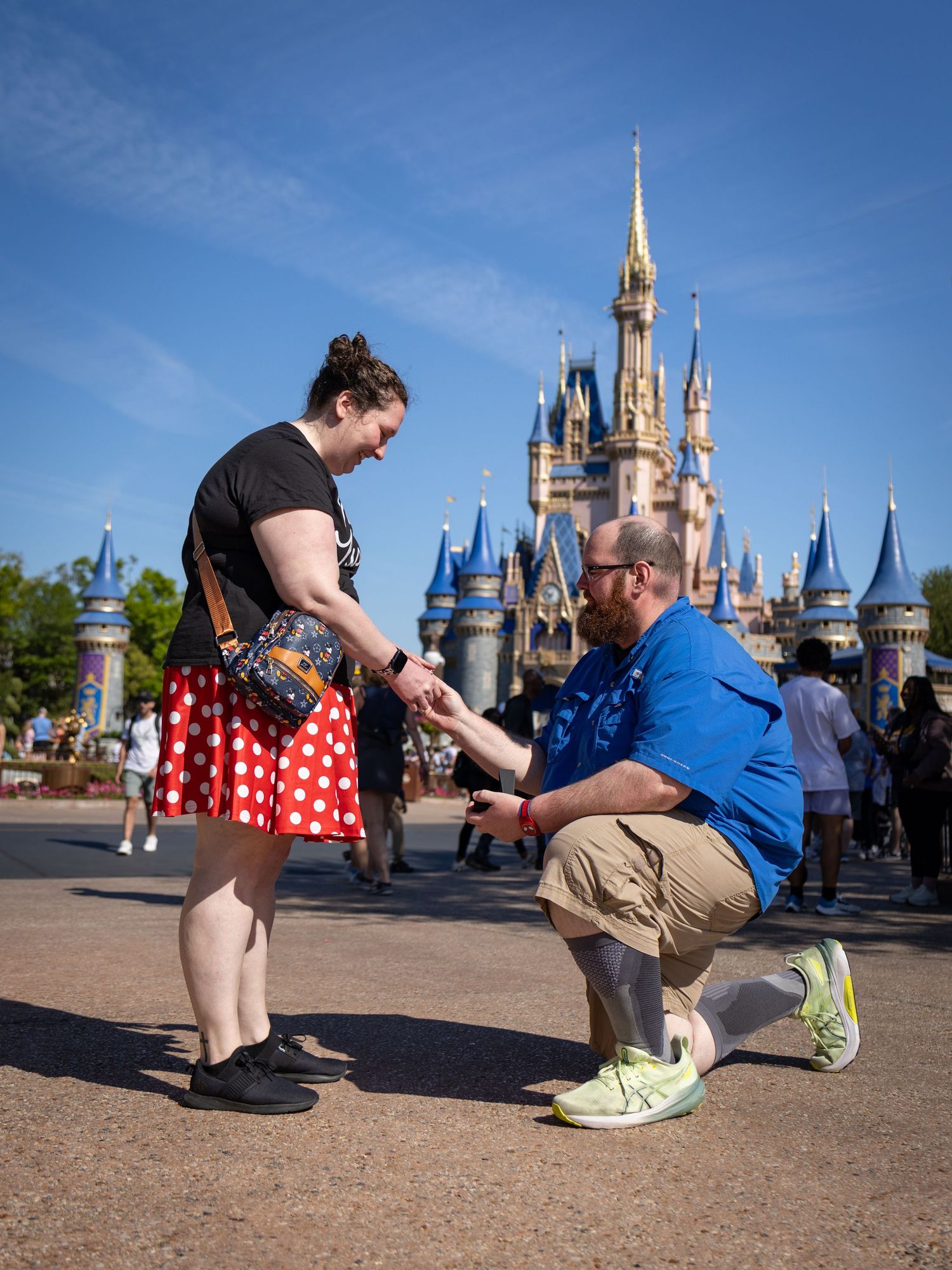 Man proposes to woman in Minnie Mouse skirt in front of Cinderella Castle at Walt Disney World Magic Kingdom.