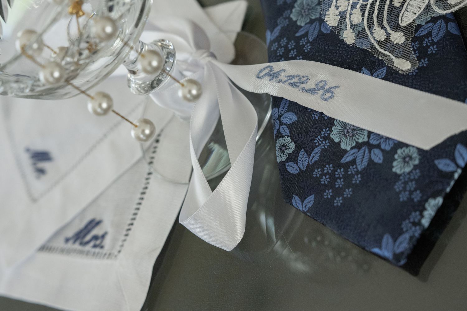 Wedding accessories with embroidered Mr. handkerchief, pearl jewelry, and blue floral gift box with white ribbon.