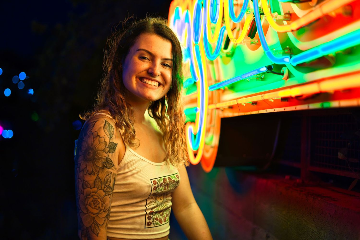 Portrait session with colorful neon signs creating vibrant nighttime atmosphere.