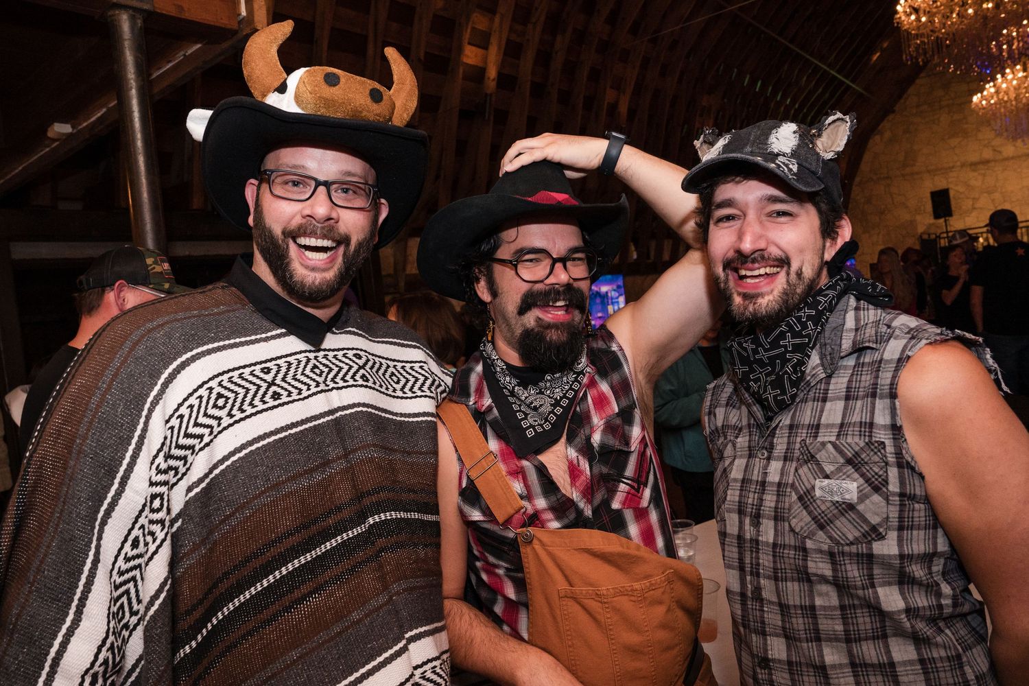 Guests celebrate and dance at a rustic barn wedding reception with western-themed attire.
