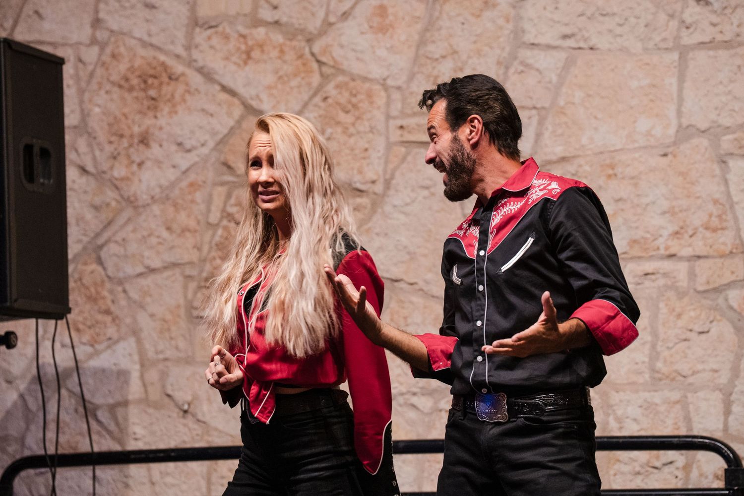 Couple performs an energetic dance routine on stage at an indoor venue.