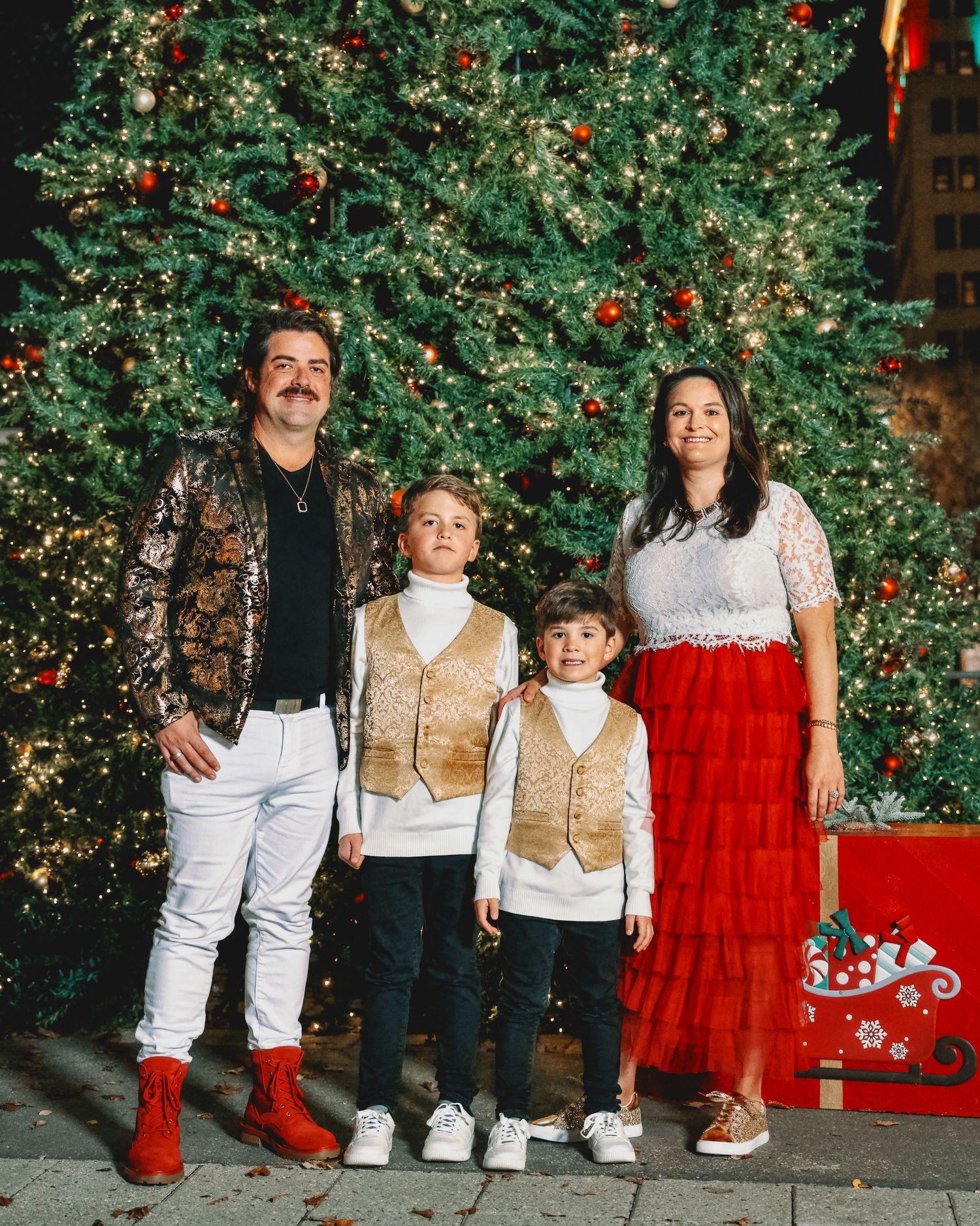 Holiday family portrait sequence in coordinated outfits against decorated greenery.