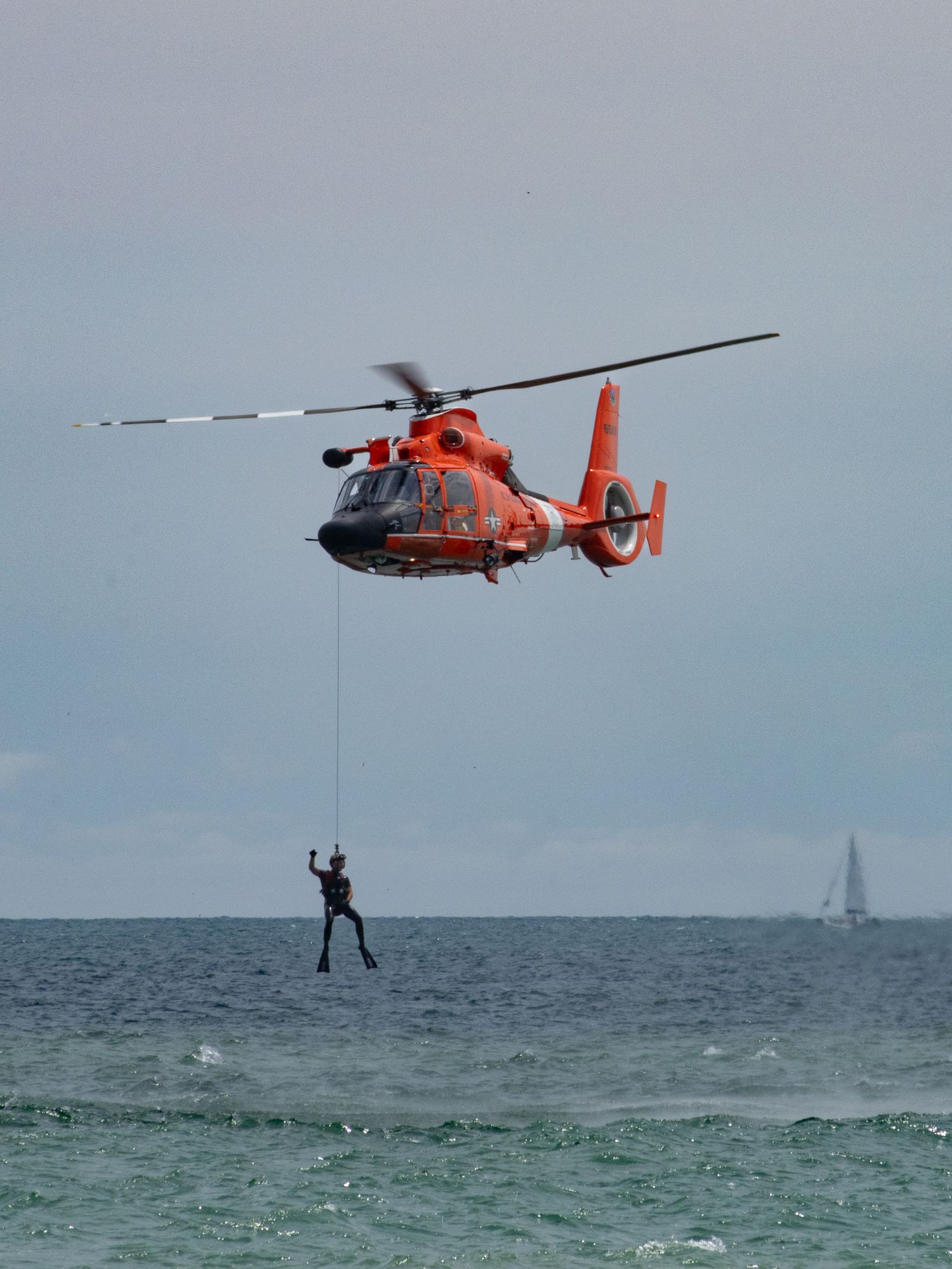 Coastguard helicopter hovering above water lifting diver