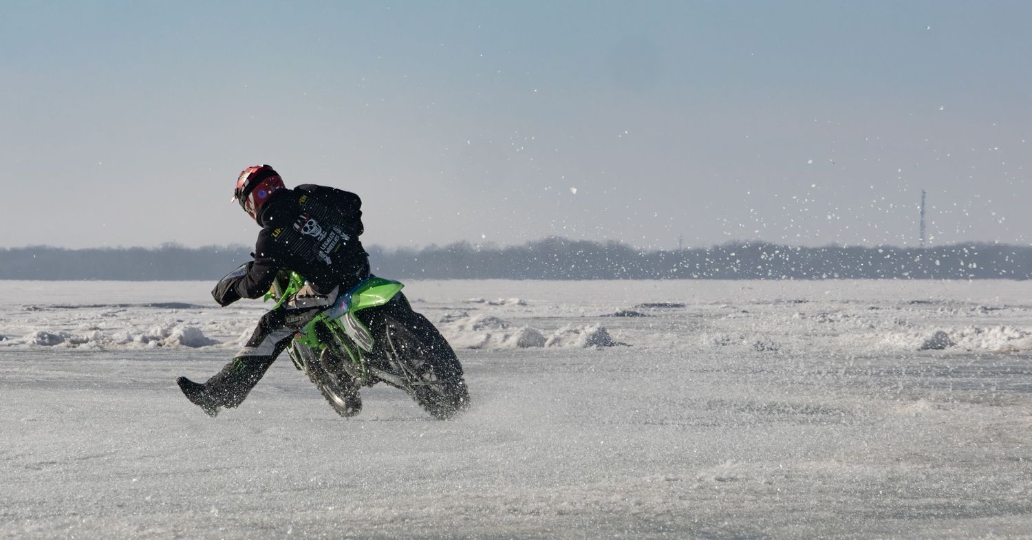 Green dirt bike racing on frozen lake