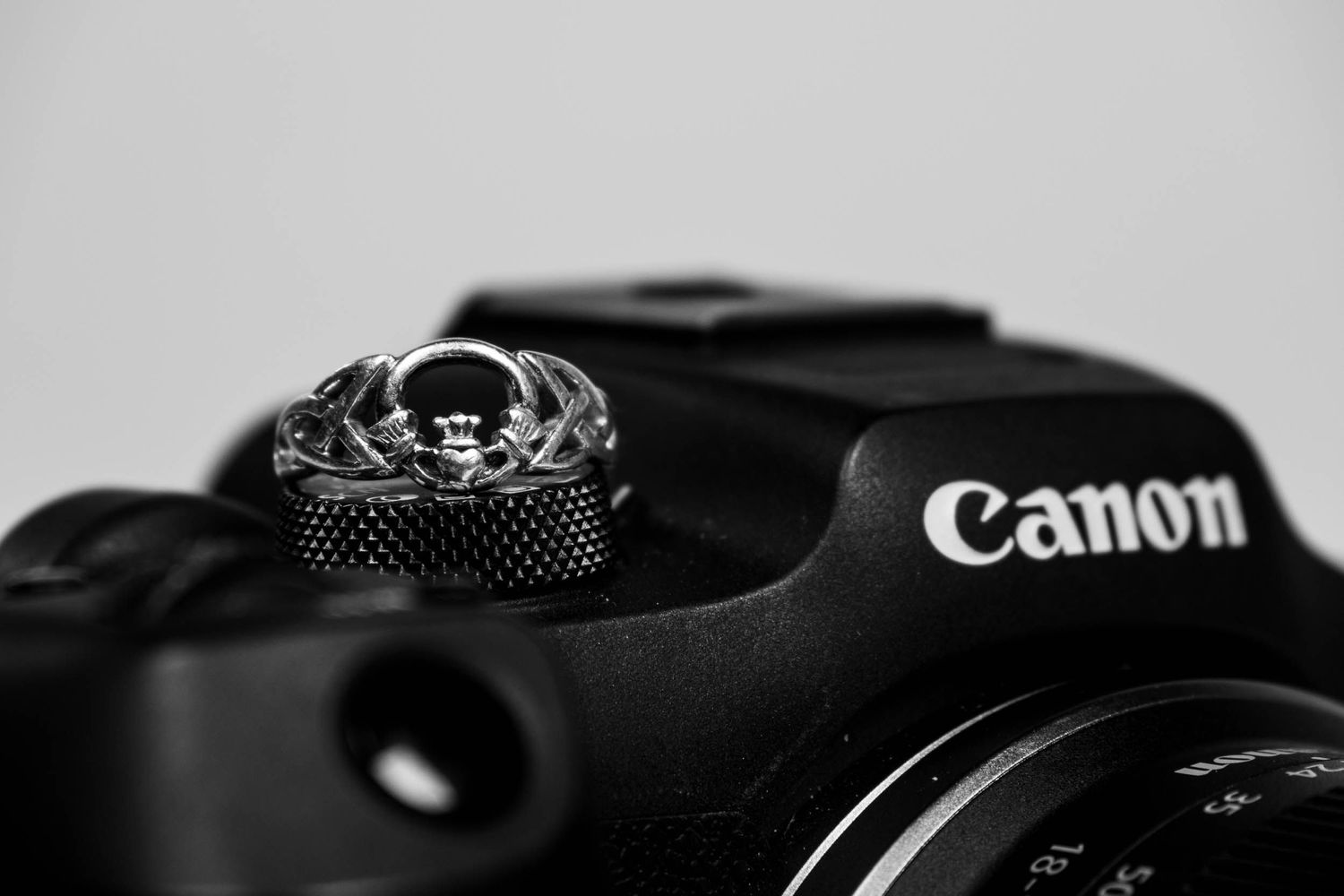 Canon camera with claddagh ring sitting on top of it