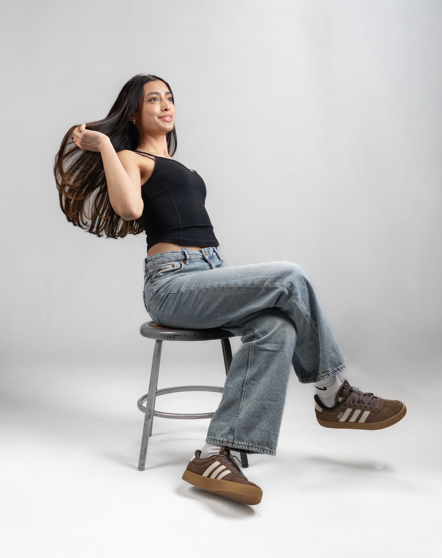 Female model sat on stool in front of white seamless background