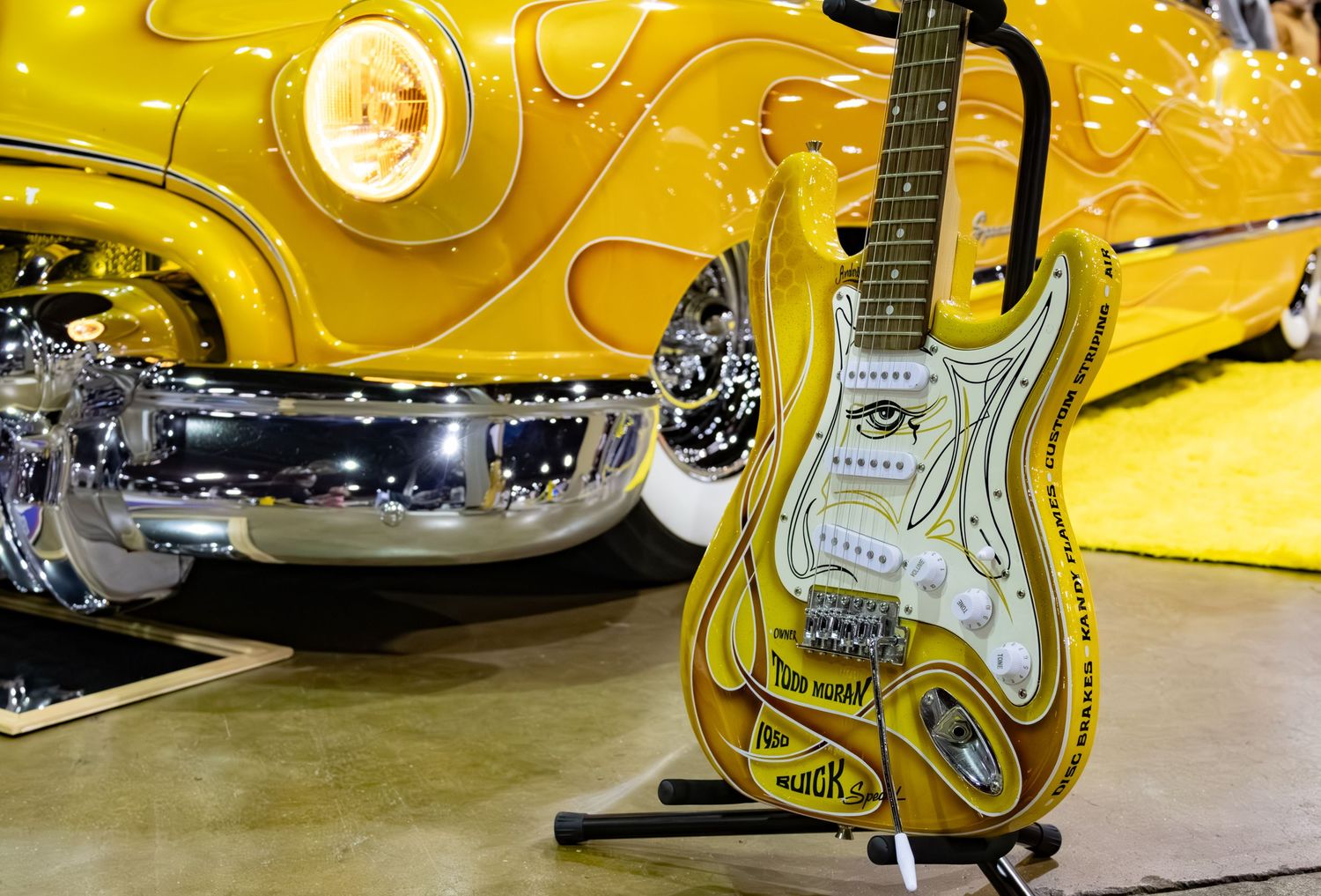 Yellow electric guitar in front of matching Buick