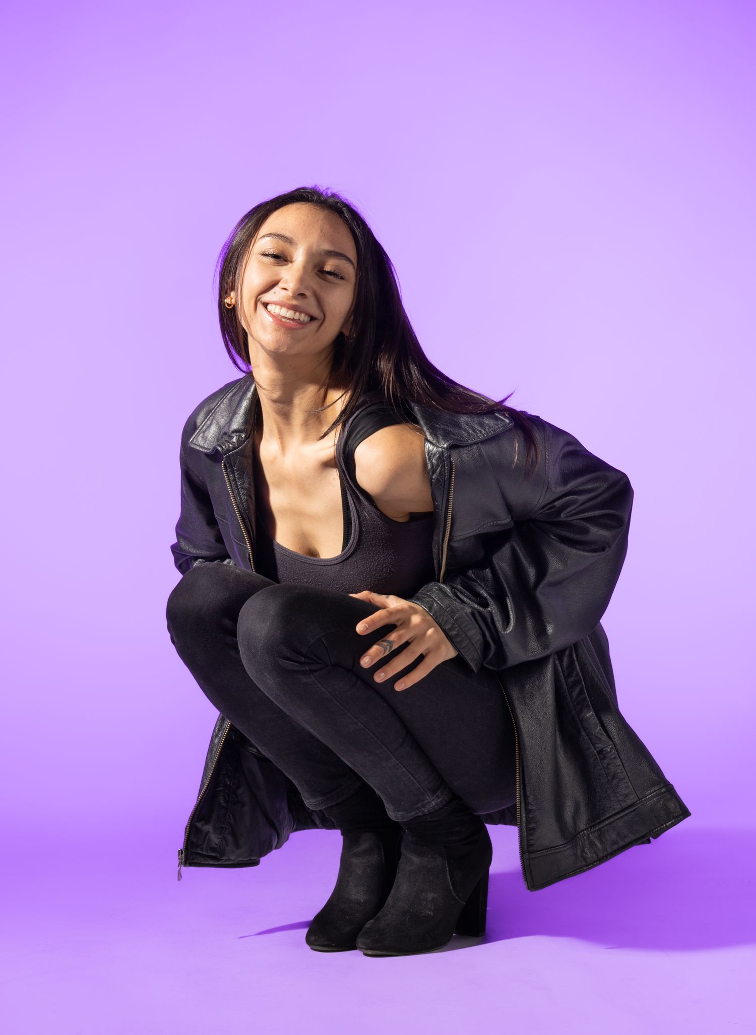 Female model posed crouching in front of purple background