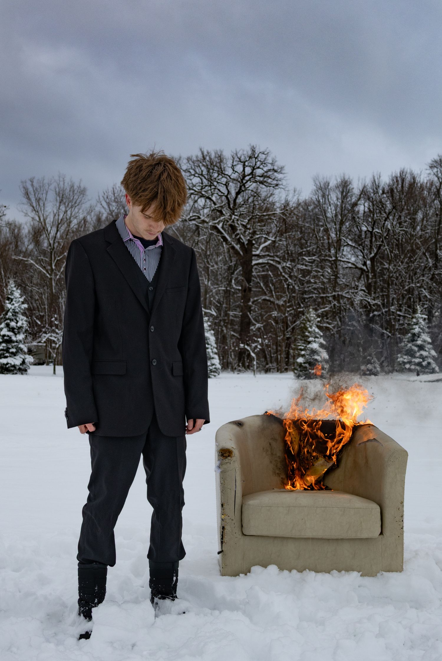 Male model standing in front of burning chair in the snow