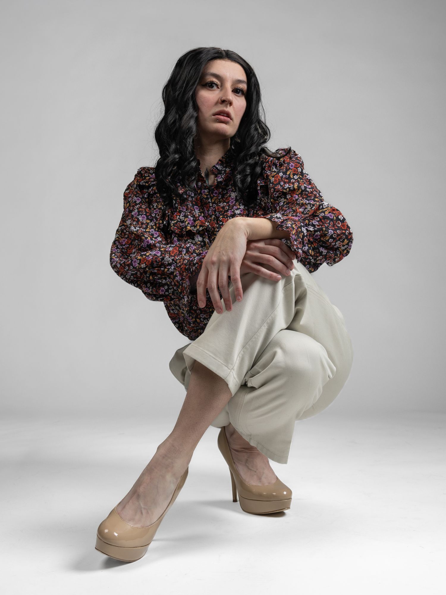 Female model posed crouched on the ground in front of white seamless background