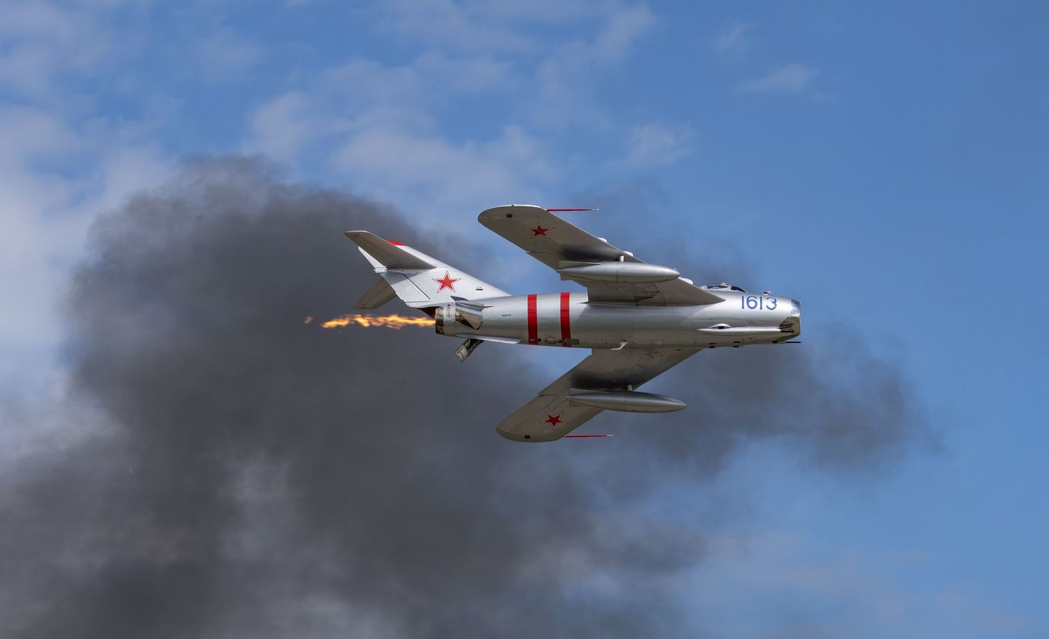 MiG-17 flying with afterburner in front of black smoke cloud