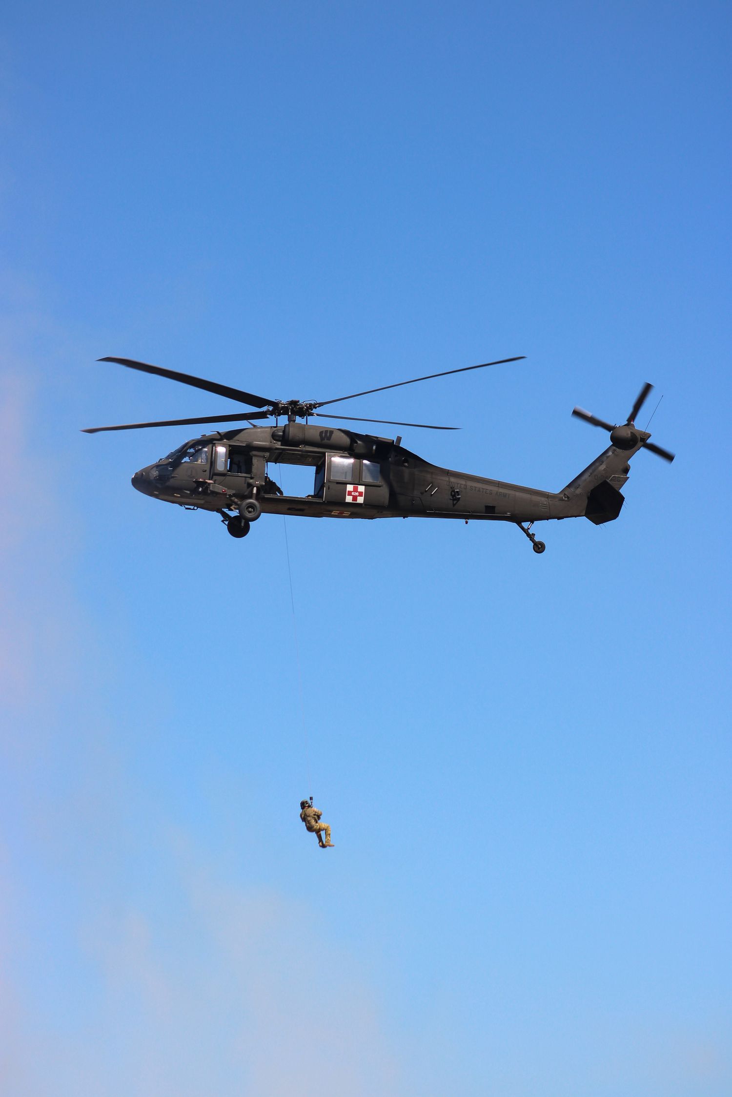 Soldier hanging on rope from medic Blackhawk helicopter