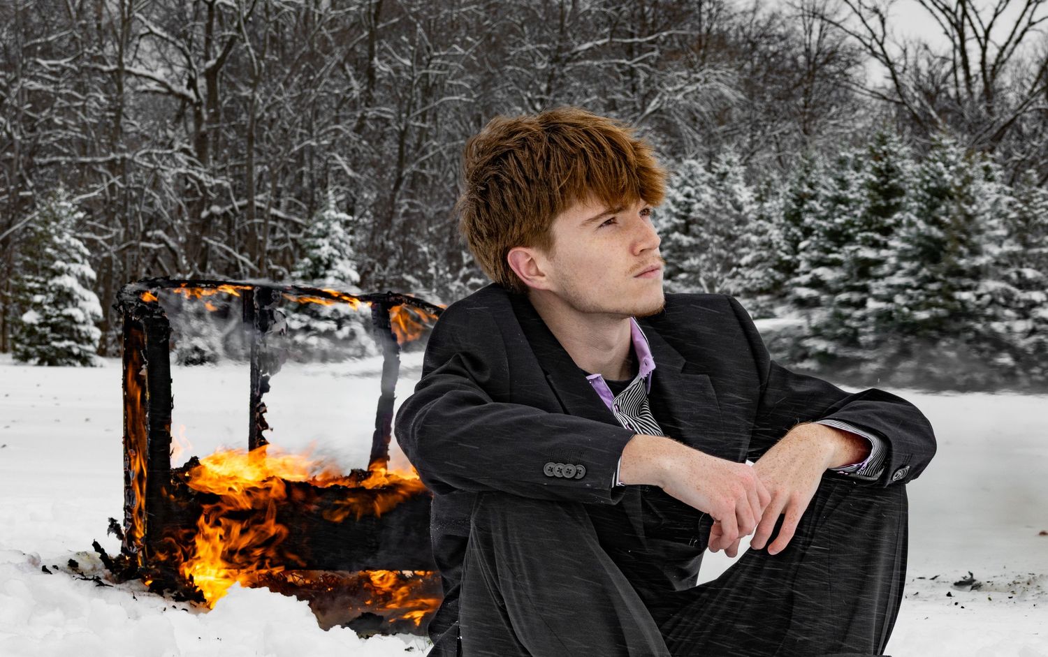 Male model sitting in front of burning chair in the snow