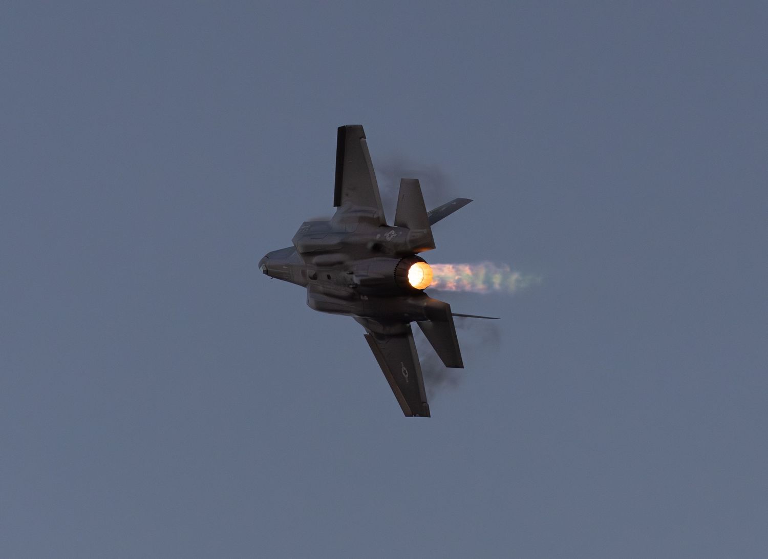 F-35 Lightning flying with afterburner and vapor around the wings