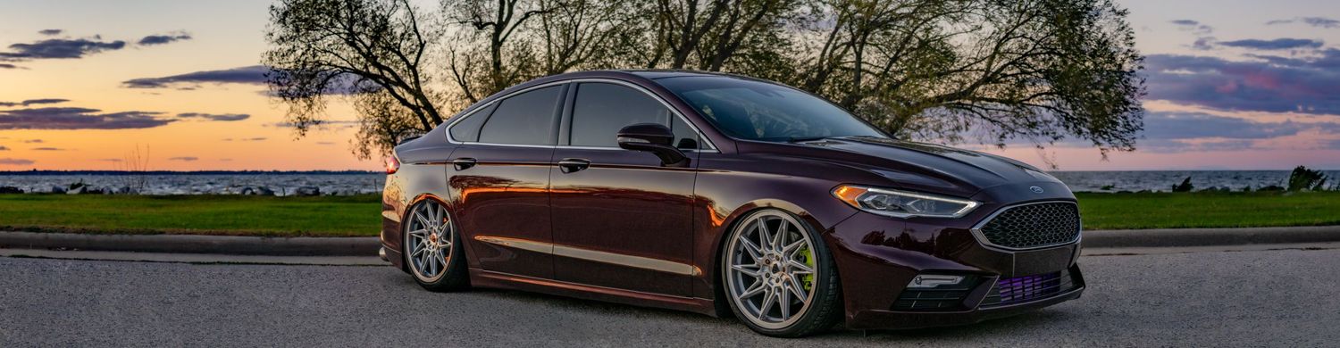 Panoramic photo of 2017 burgundy Ford Fusion Sport in front of a lake during sunset