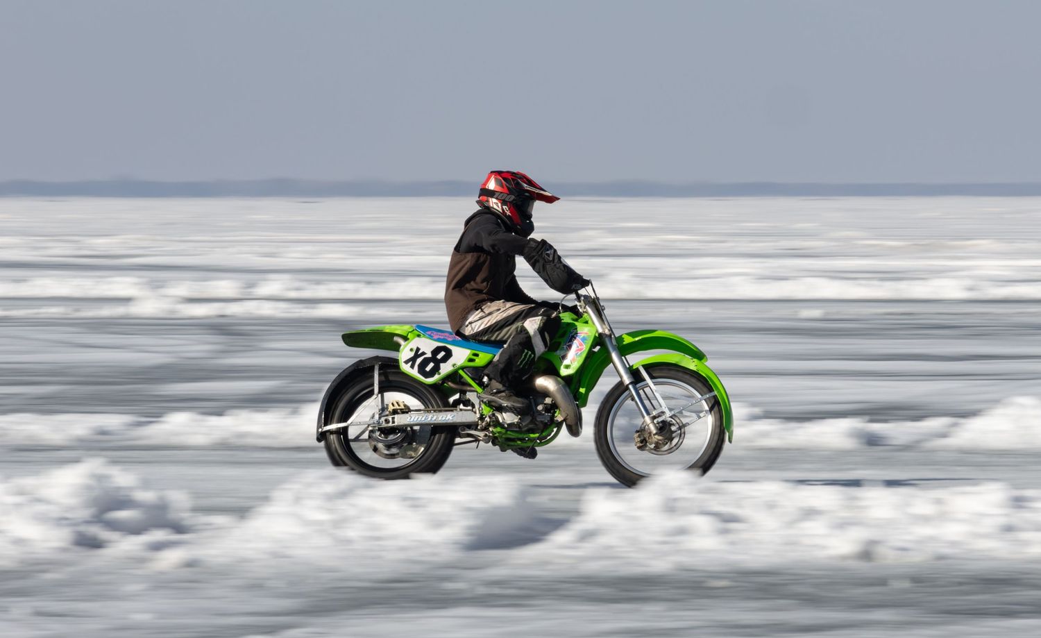 Green dirt bike racing on frozen lake