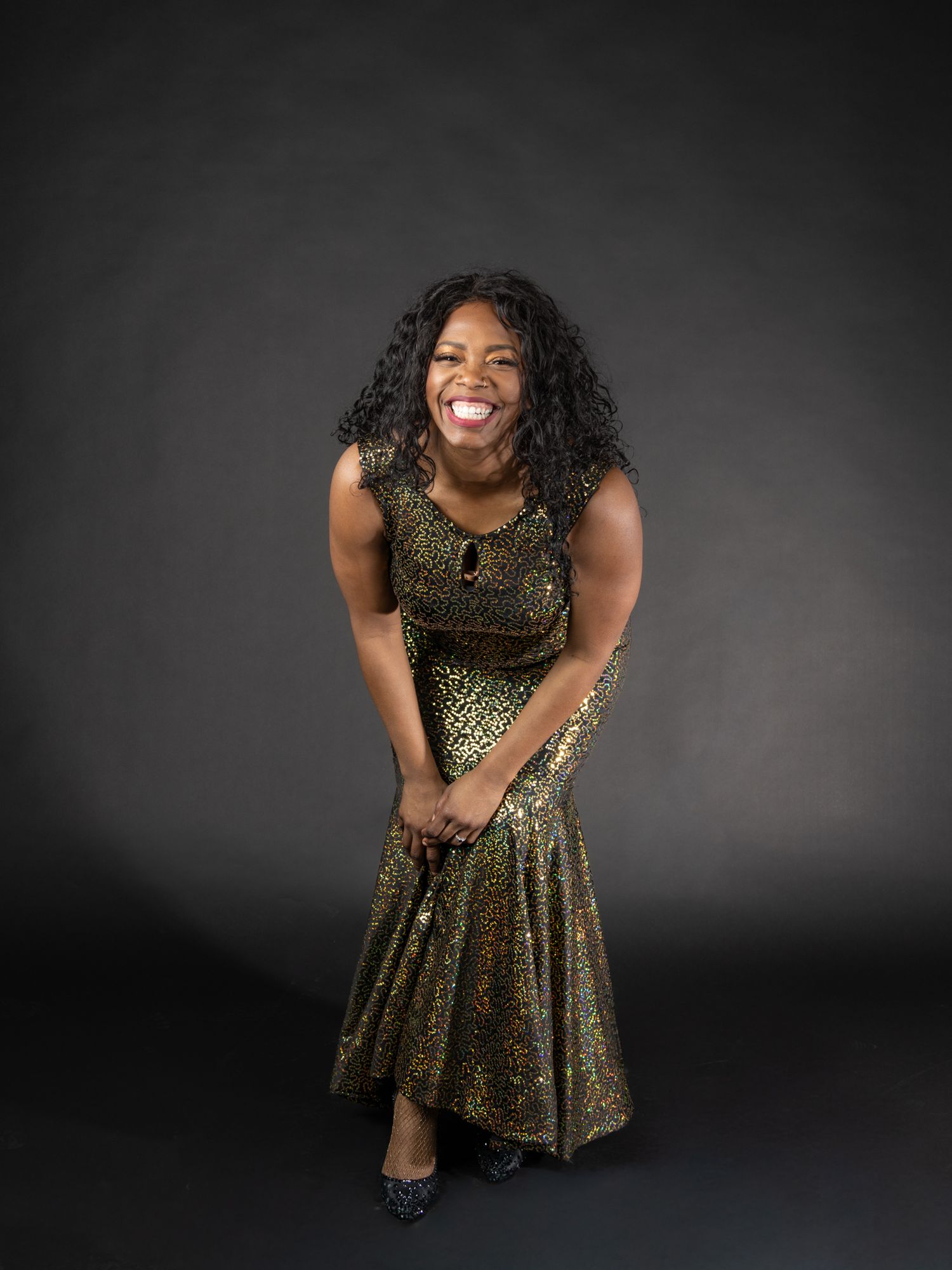 Female model in gold sequin dress in front of black seamless background