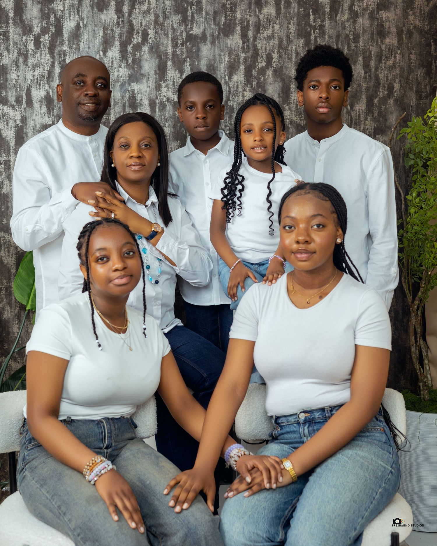 Family portrait series with coordinated white tops and jeans against textured grey background.