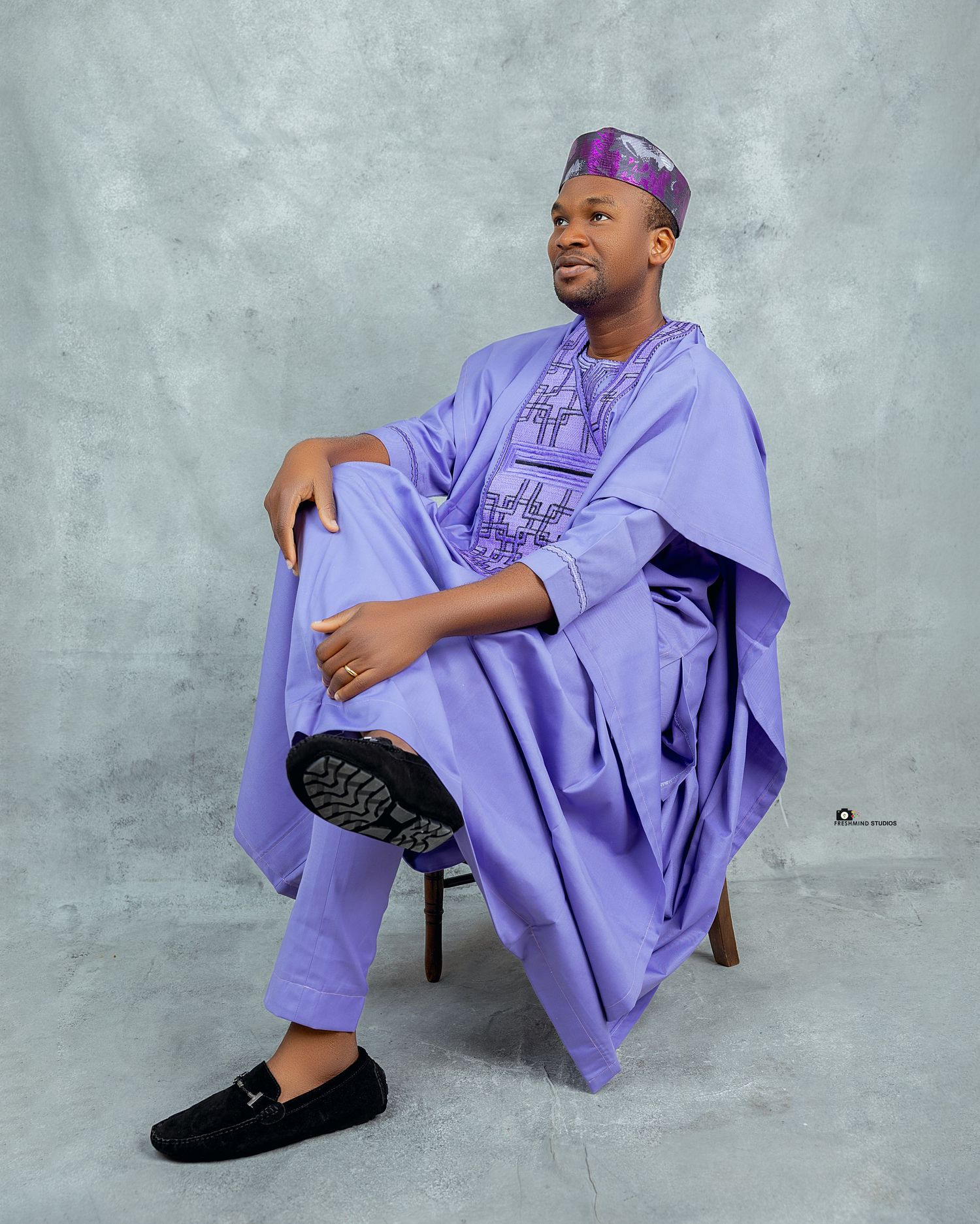 Purple traditional African agbada outfit photographed against grey background.