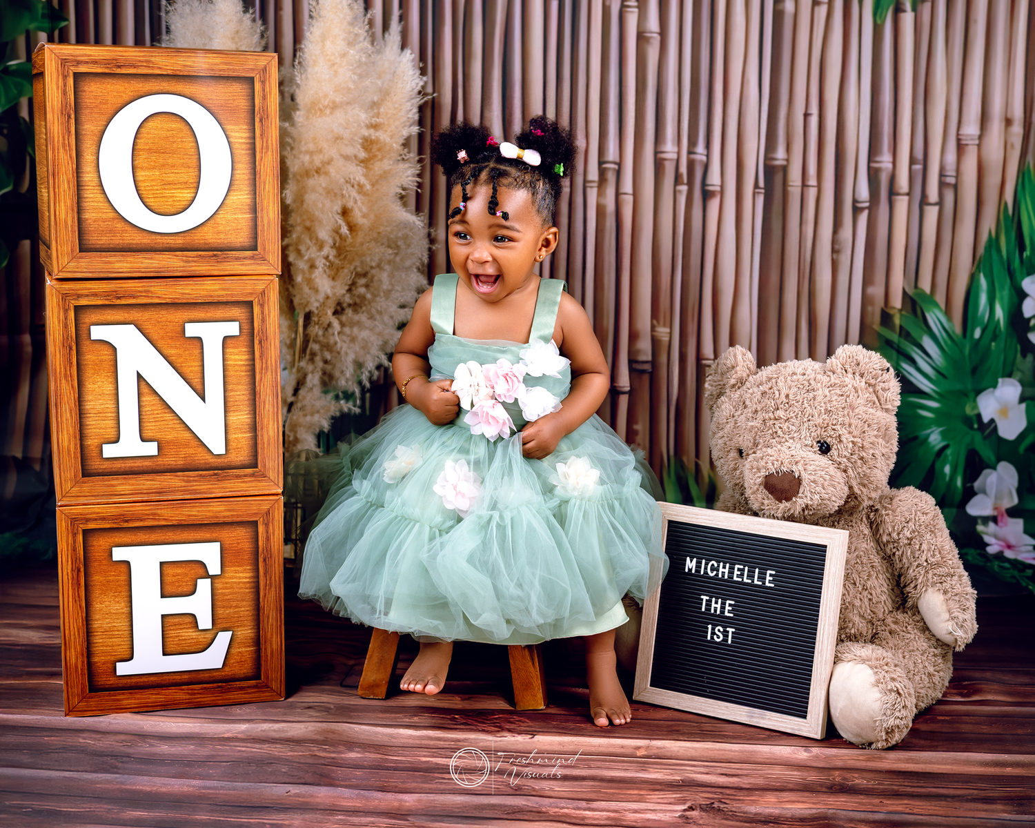 Birthday photoshoot setup with mint tutu dress, teddy bear, and wooden letter blocks.