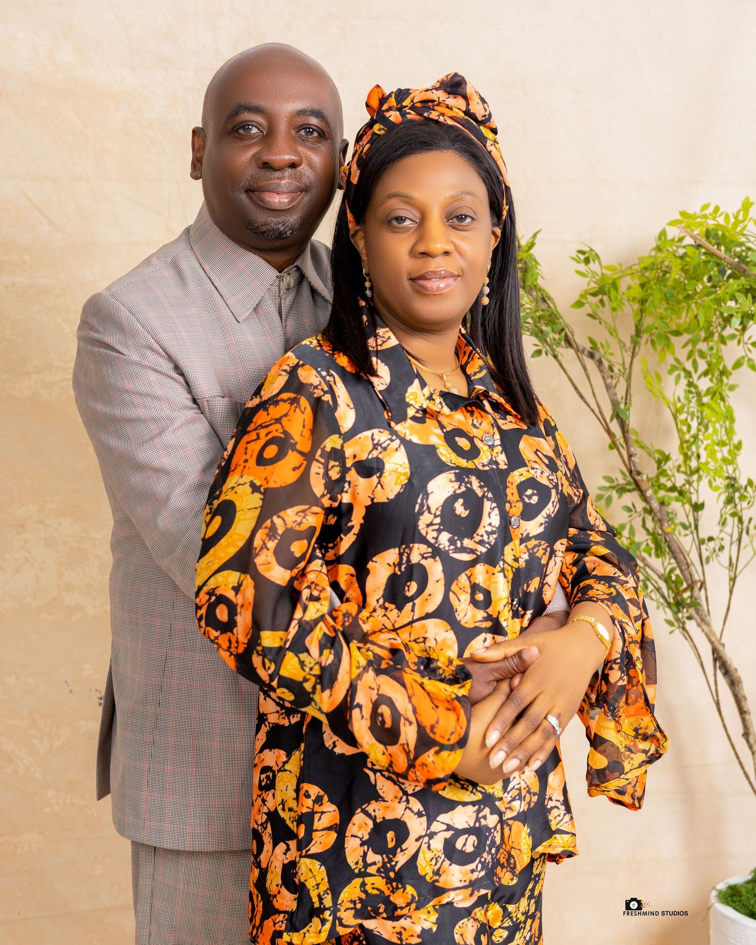 Couple poses in coordinated outfits with person wearing vibrant orange and black patterned dress.