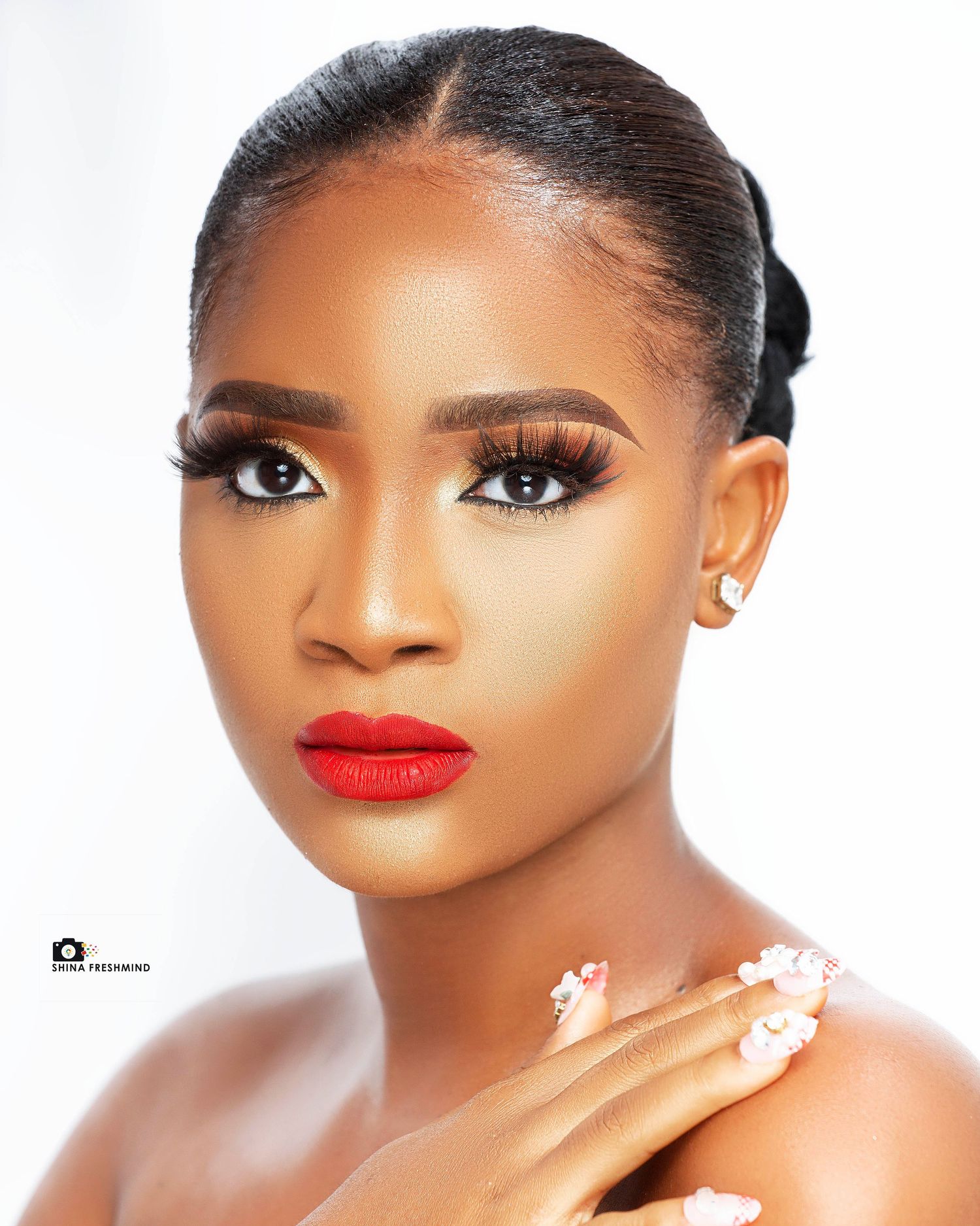 Close-up beauty portrait with glamorous makeup, red lips and sleek hairstyle against white background.