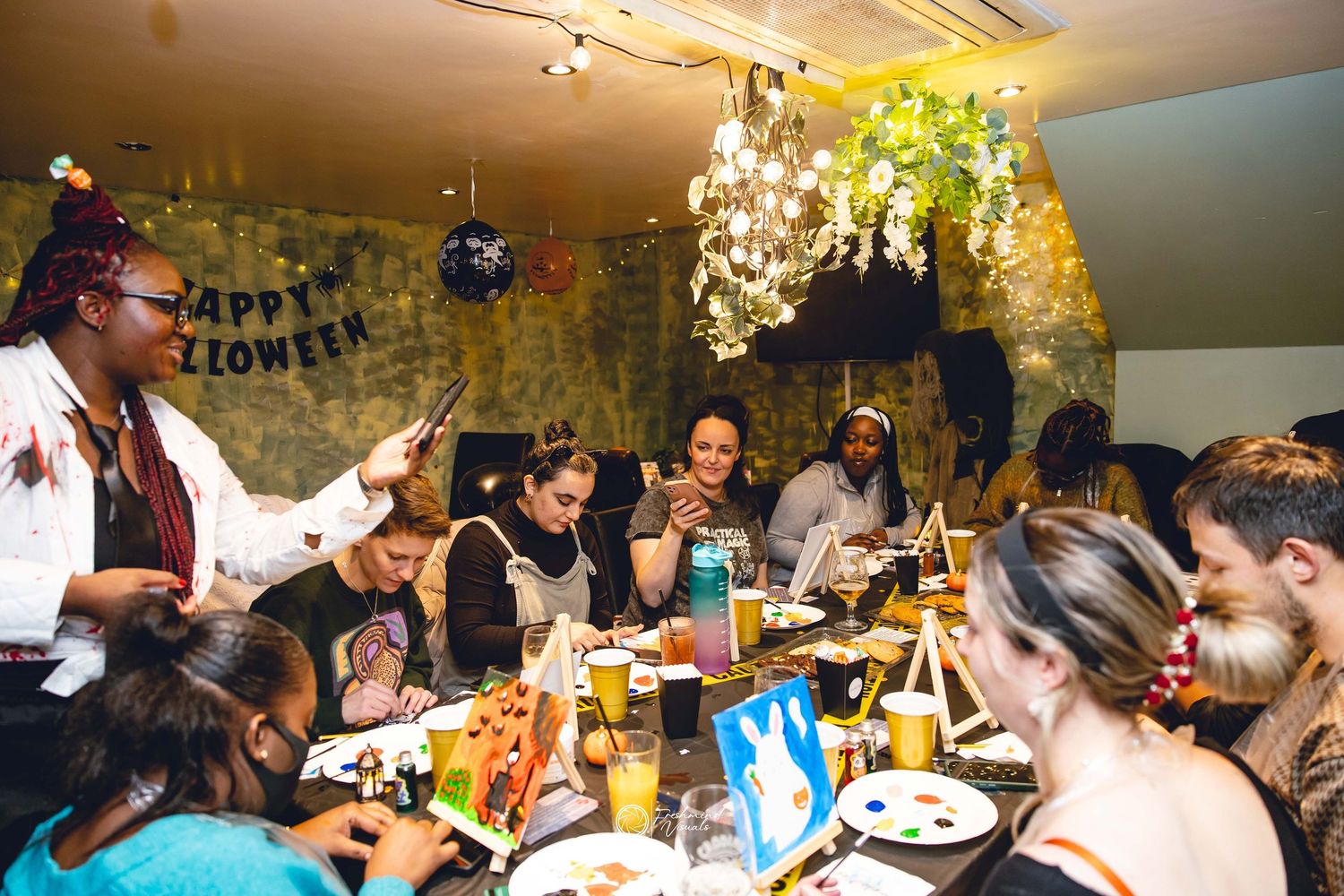 A group of people gathered around a dining table celebrating with food and drinks at a festive party gathering.
