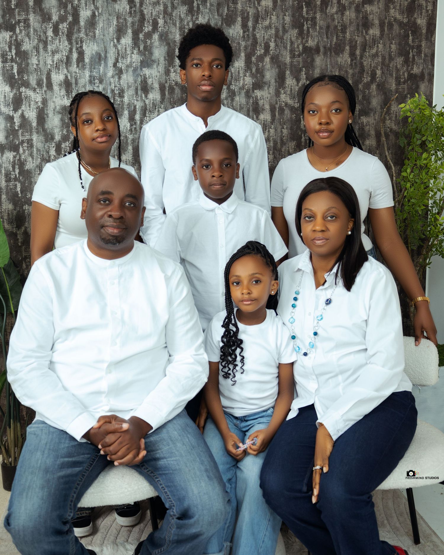 Family portrait of seven people wearing coordinated white and blue casual outfits.