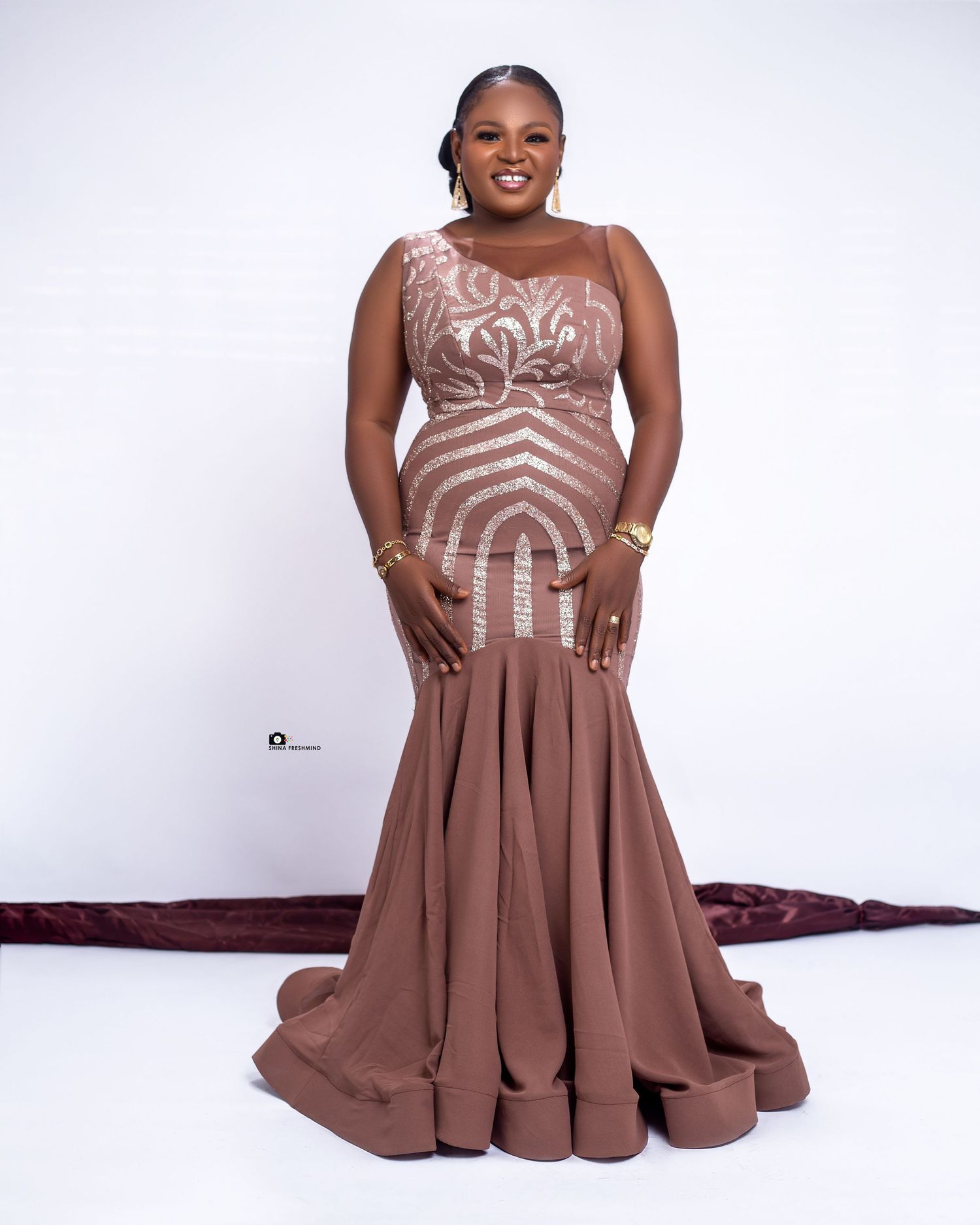 Full-length photo of someone in a brown mermaid gown with intricate beaded patterns.