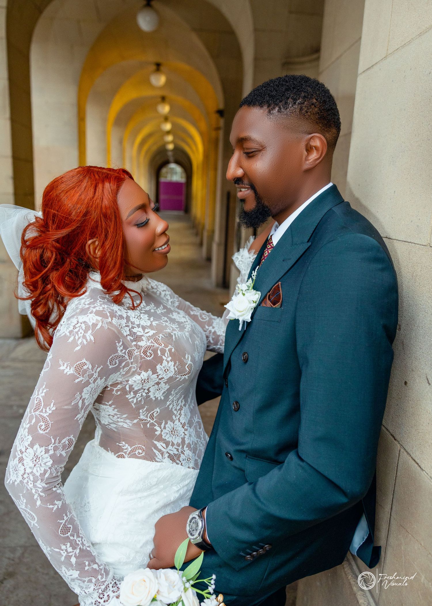 Romantic wedding couple shares intimate moments in an elegant arched hallway with stone columns and warm lighting.