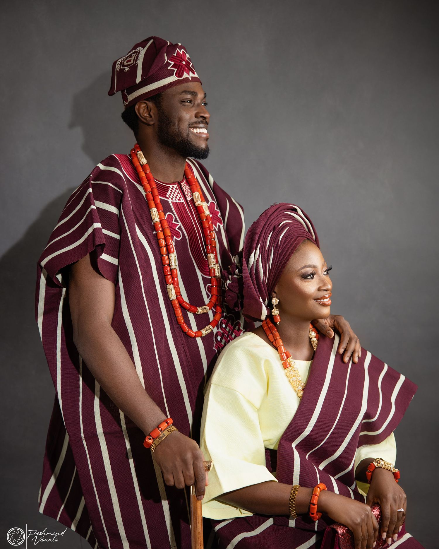Couple in coordinated burgundy striped traditional outfits posing for professional photos.
