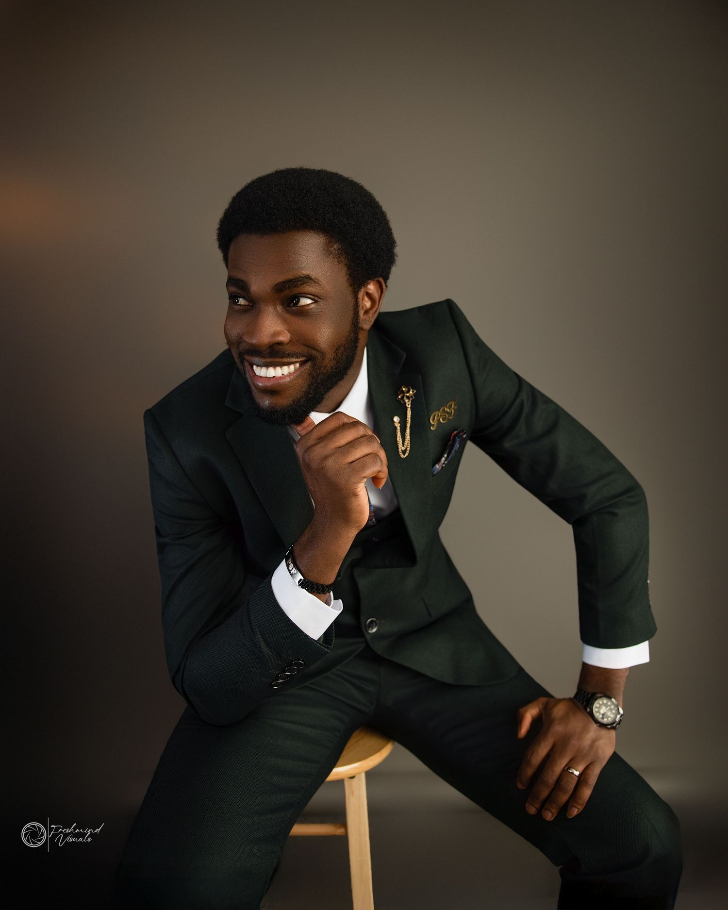 Professional studio portraits showing relaxed poses in black suit against neutral background.