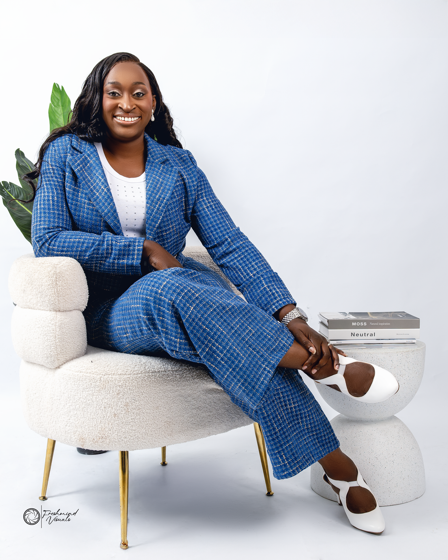 Stylish blue plaid suit lounging poses on modern white chair.