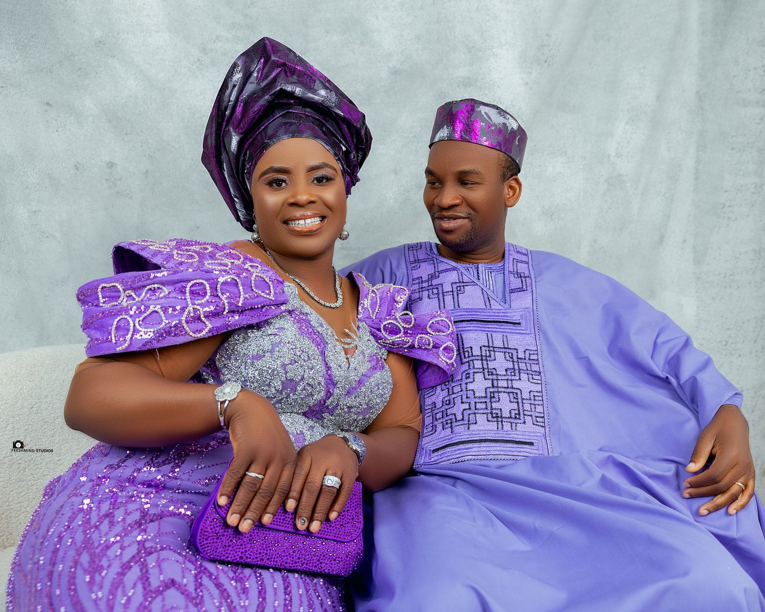 Couple wearing matching purple traditional African attire embracing in a photo series.