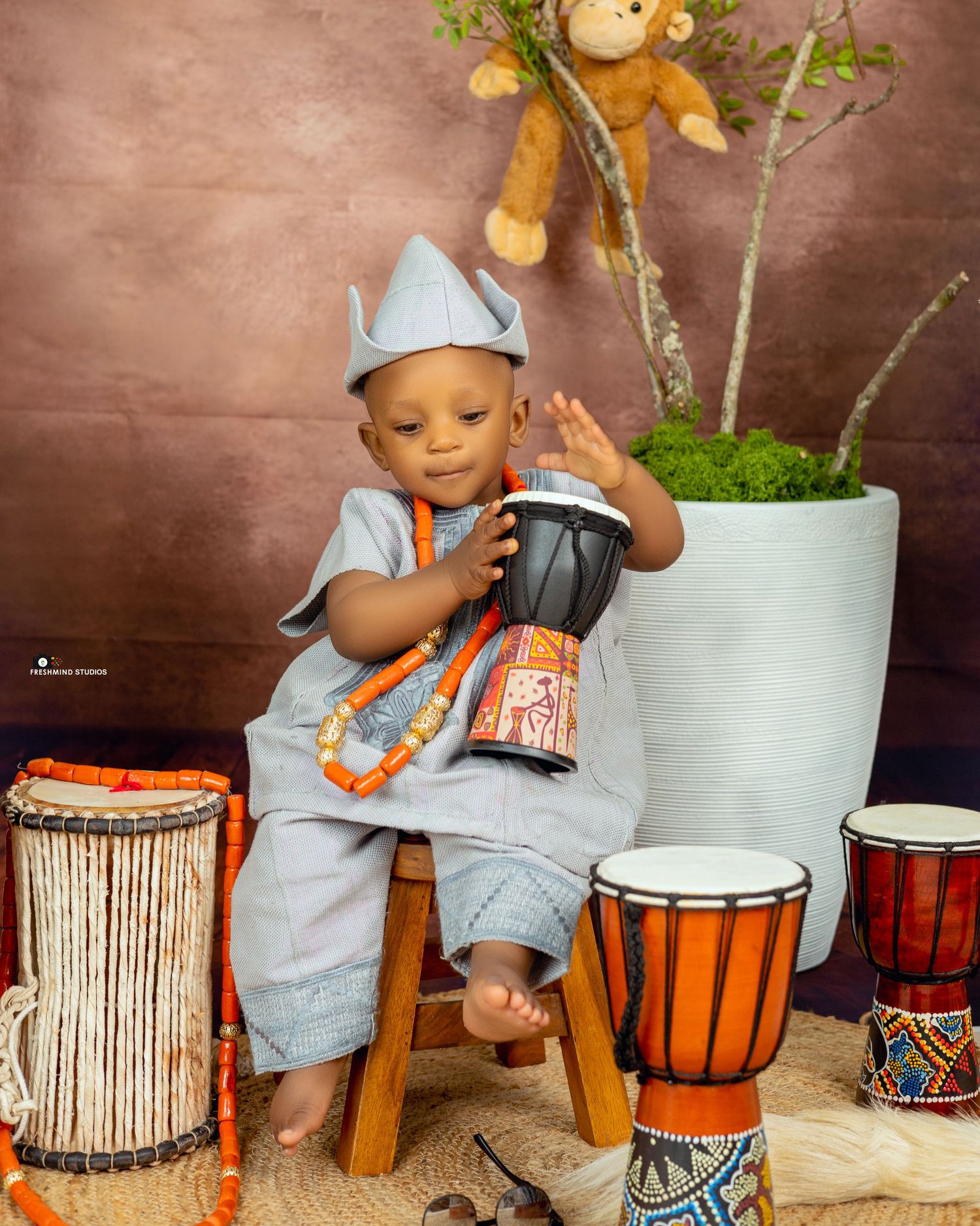 Child playing with traditional African drums and decorative elements in studio setting.
