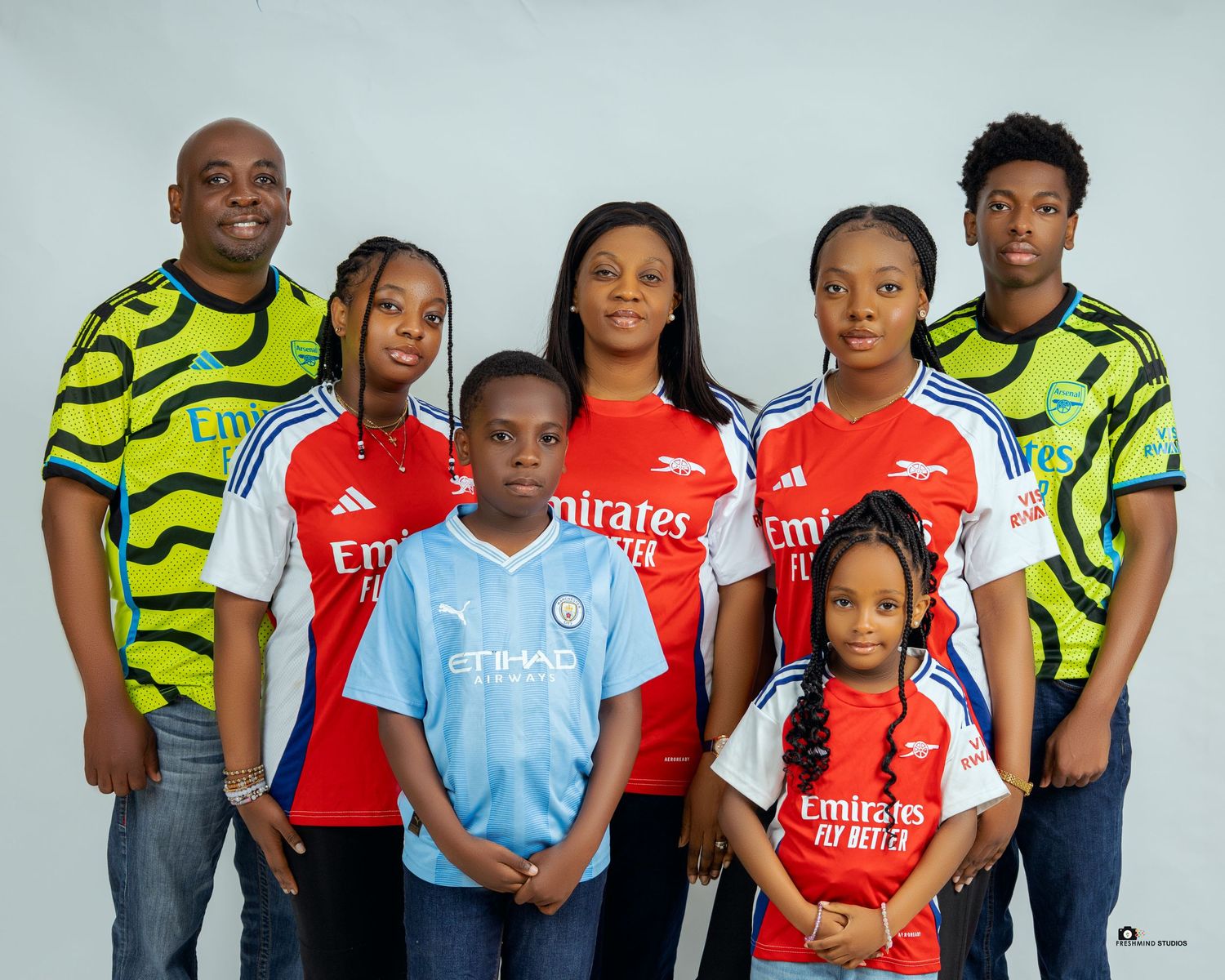 Group photo of family members wearing coordinated sports jerseys and casual attire against light background.