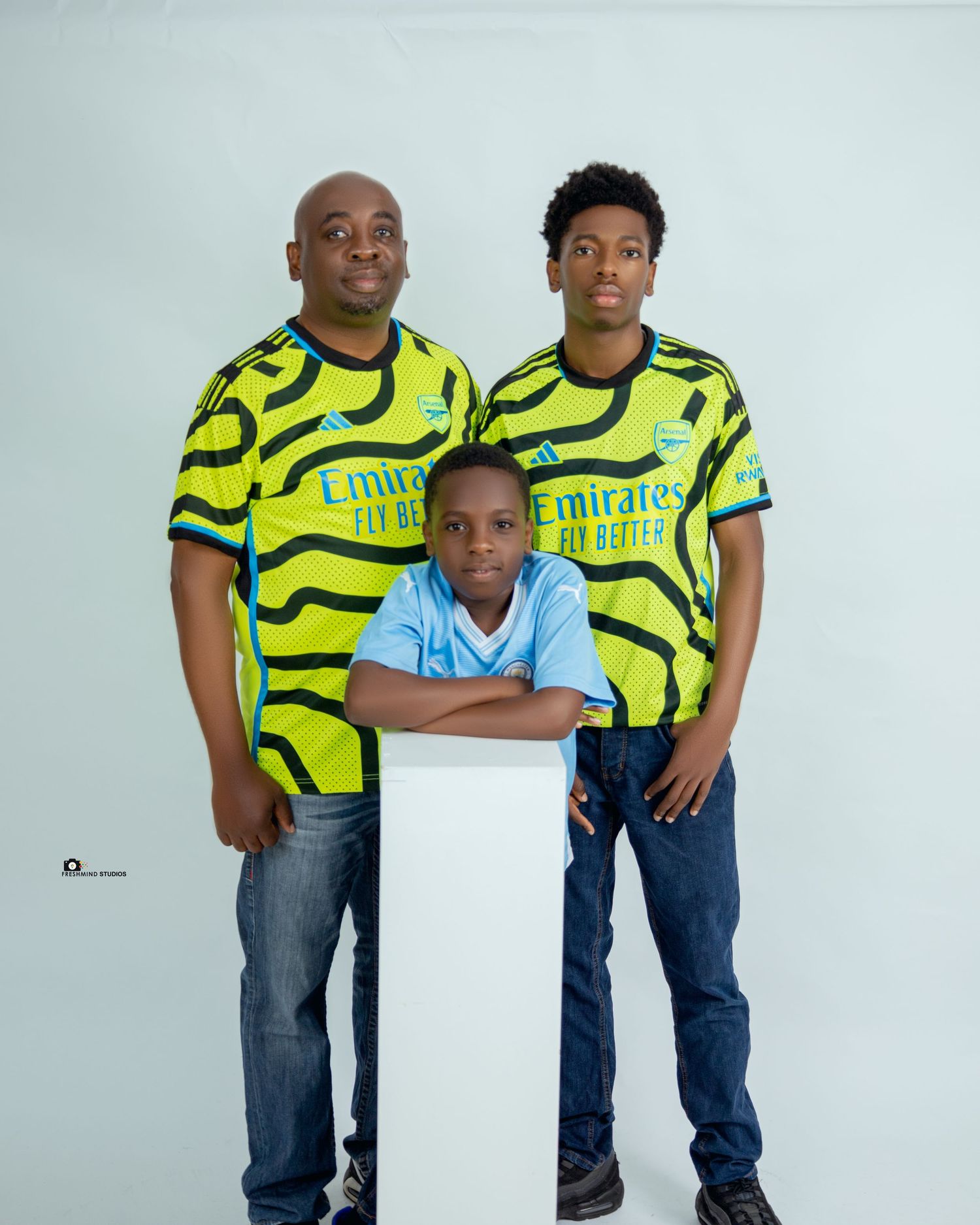 Family group wearing matching neon yellow Emirates jerseys posing against white background.