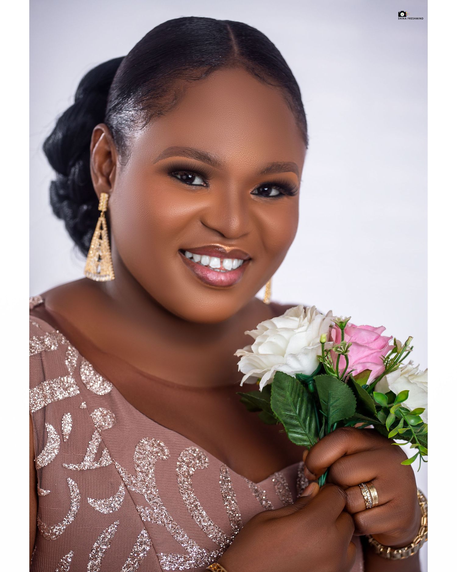 Close-up portrait with flowers showing detailed makeup and shimmering dress details.