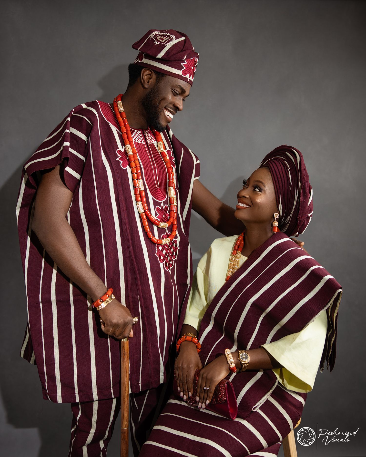 Couple in traditional Yoruba attire sharing a joyful moment.