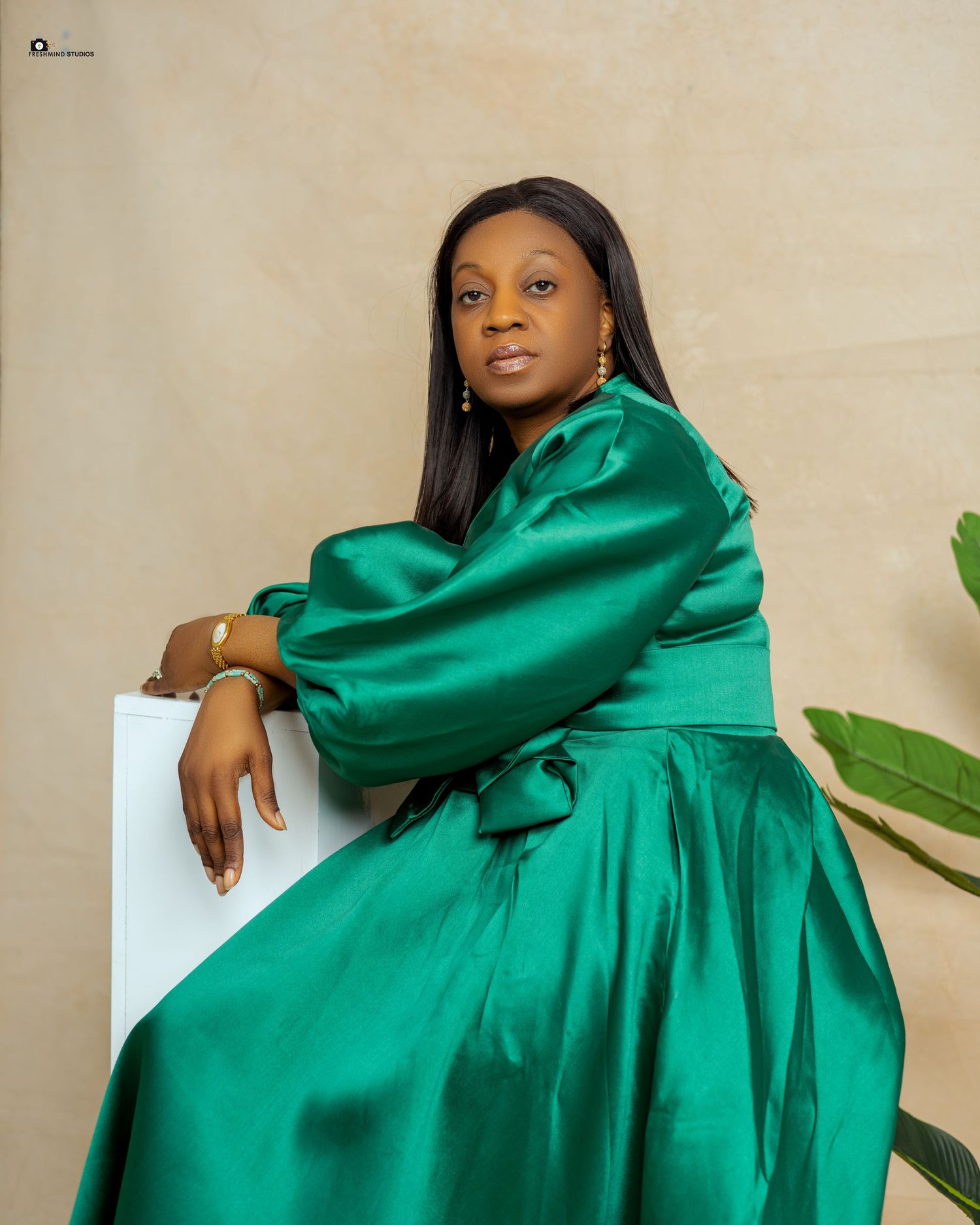 Emerald green satin dress with dramatic sleeves in elegant studio portraits.