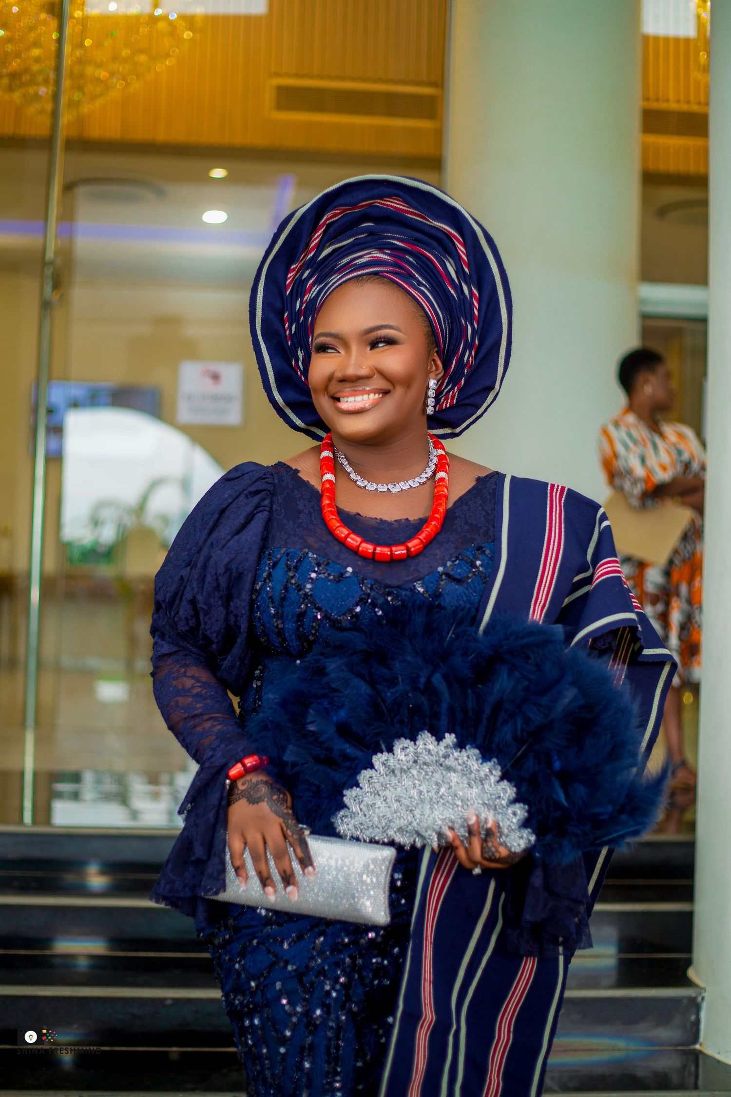 Beautiful traditional attire with navy sequined dress and decorative silver fan on marble steps.