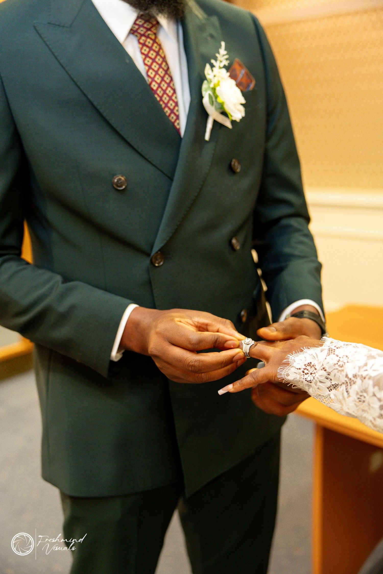 Close-up shot of hands holding delicate lace fabric against a dark suit during a formal event.