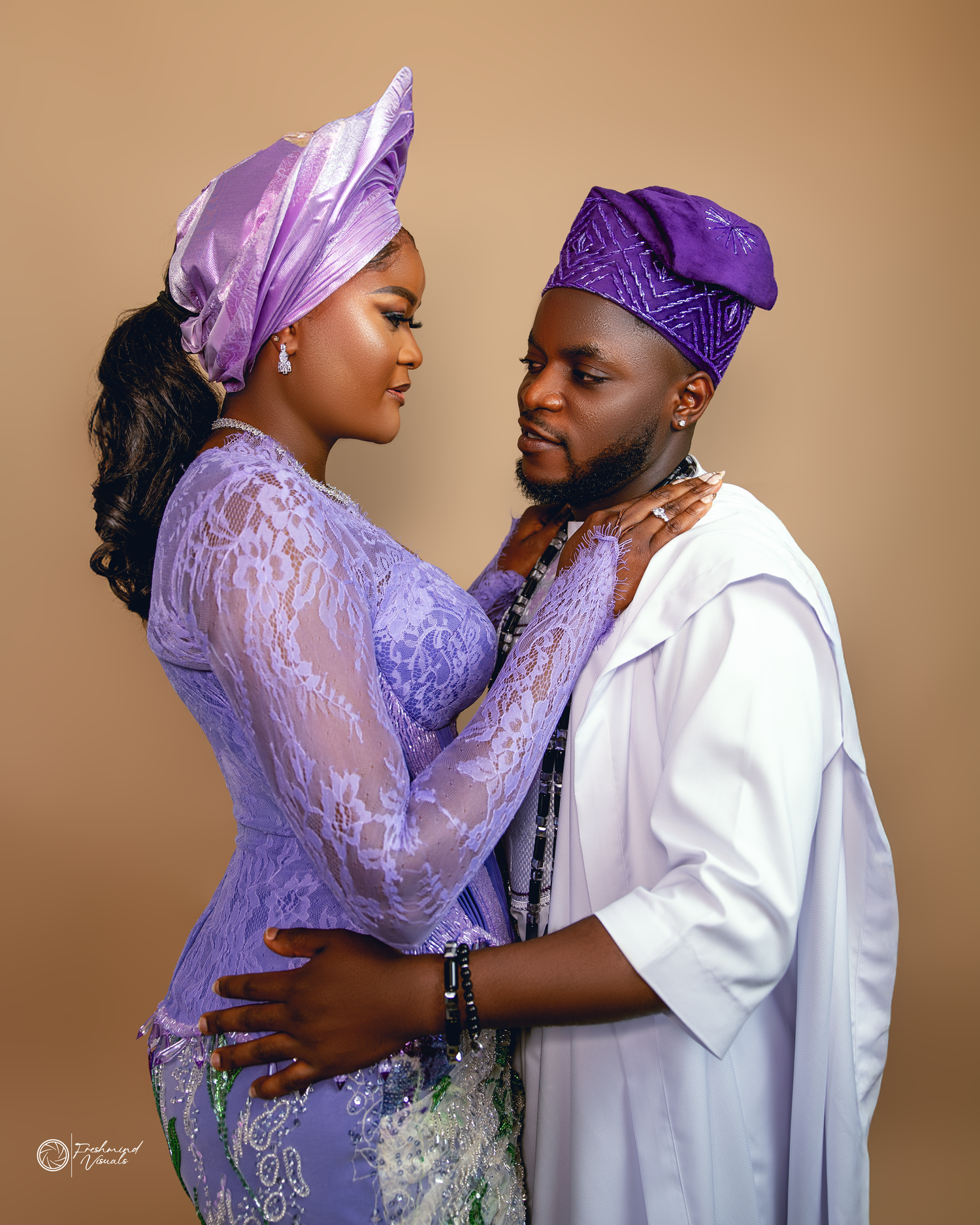 A couple in traditional Nigerian attire share intimate moments in purple and white outfits during a romantic photoshoot.