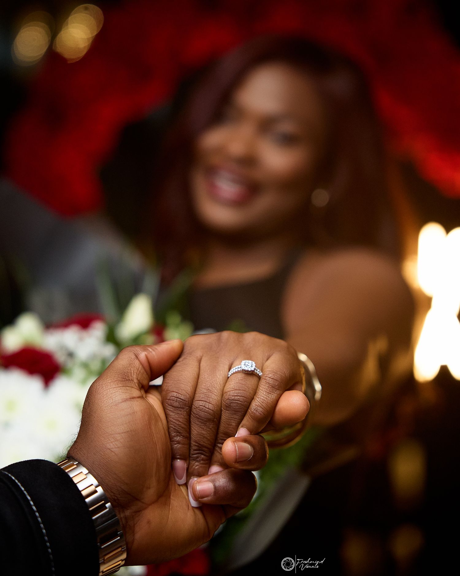 Close-up of hands showing engagement ring with romantic lighting.