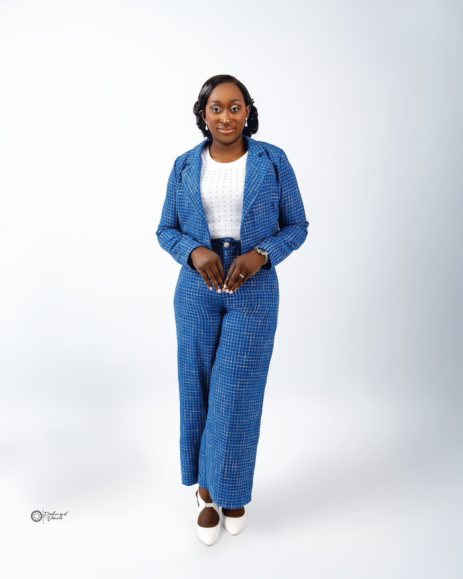 Professional fashion shoot featuring bright blue plaid coat ensemble against white background.