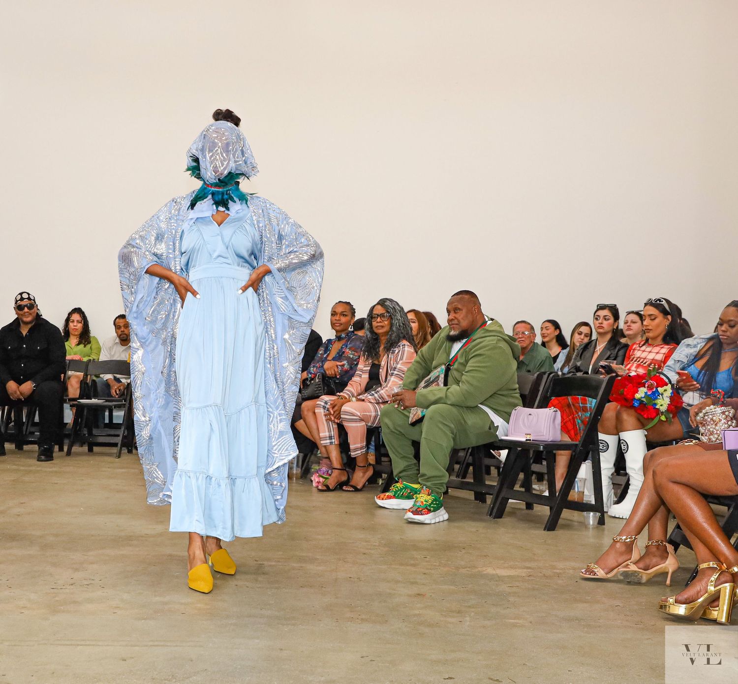 Fashion show featuring light colored garments in a contemporary gallery setting.