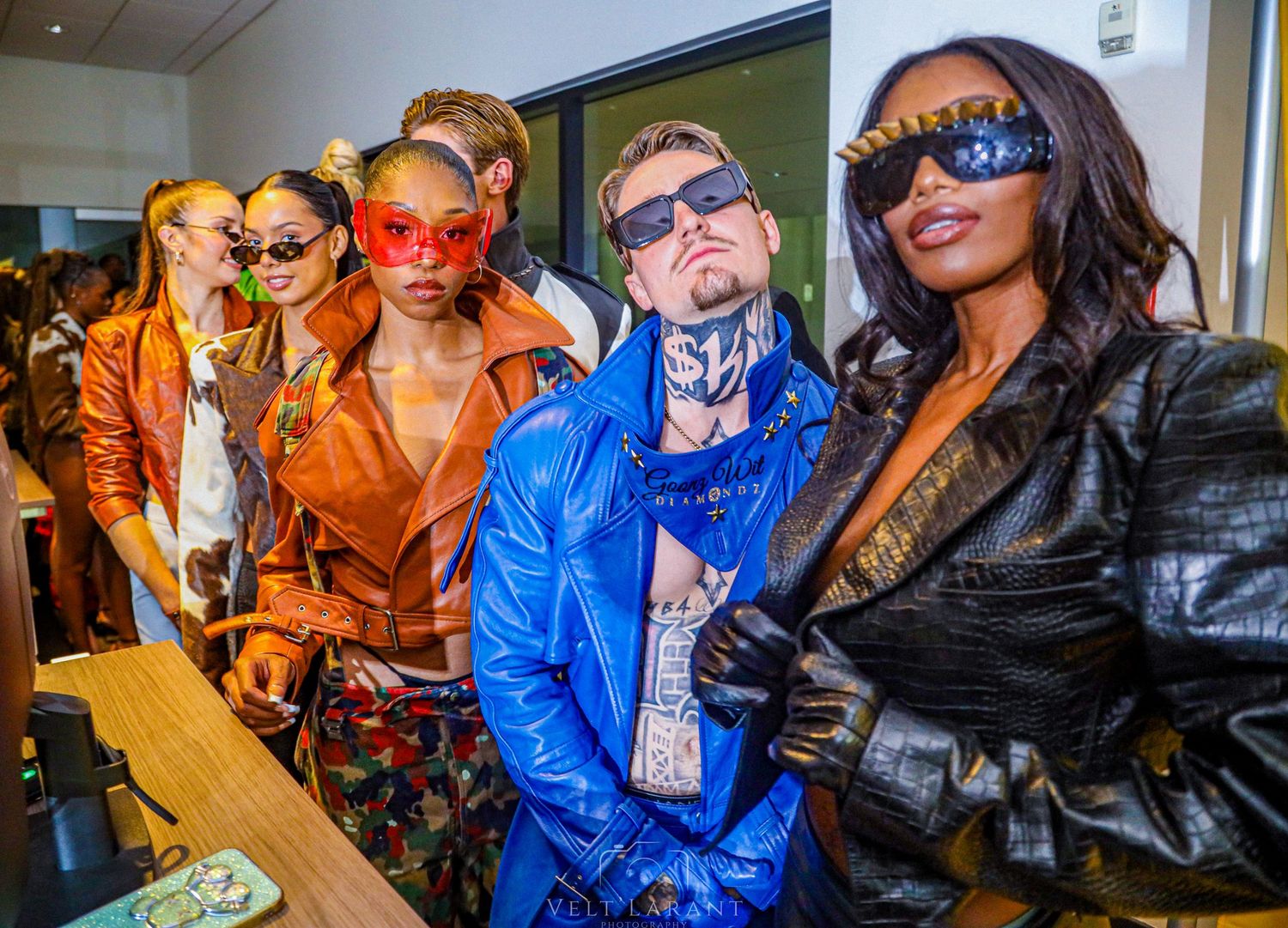 Group wearing colorful leather jackets and sunglasses pose together at an event.